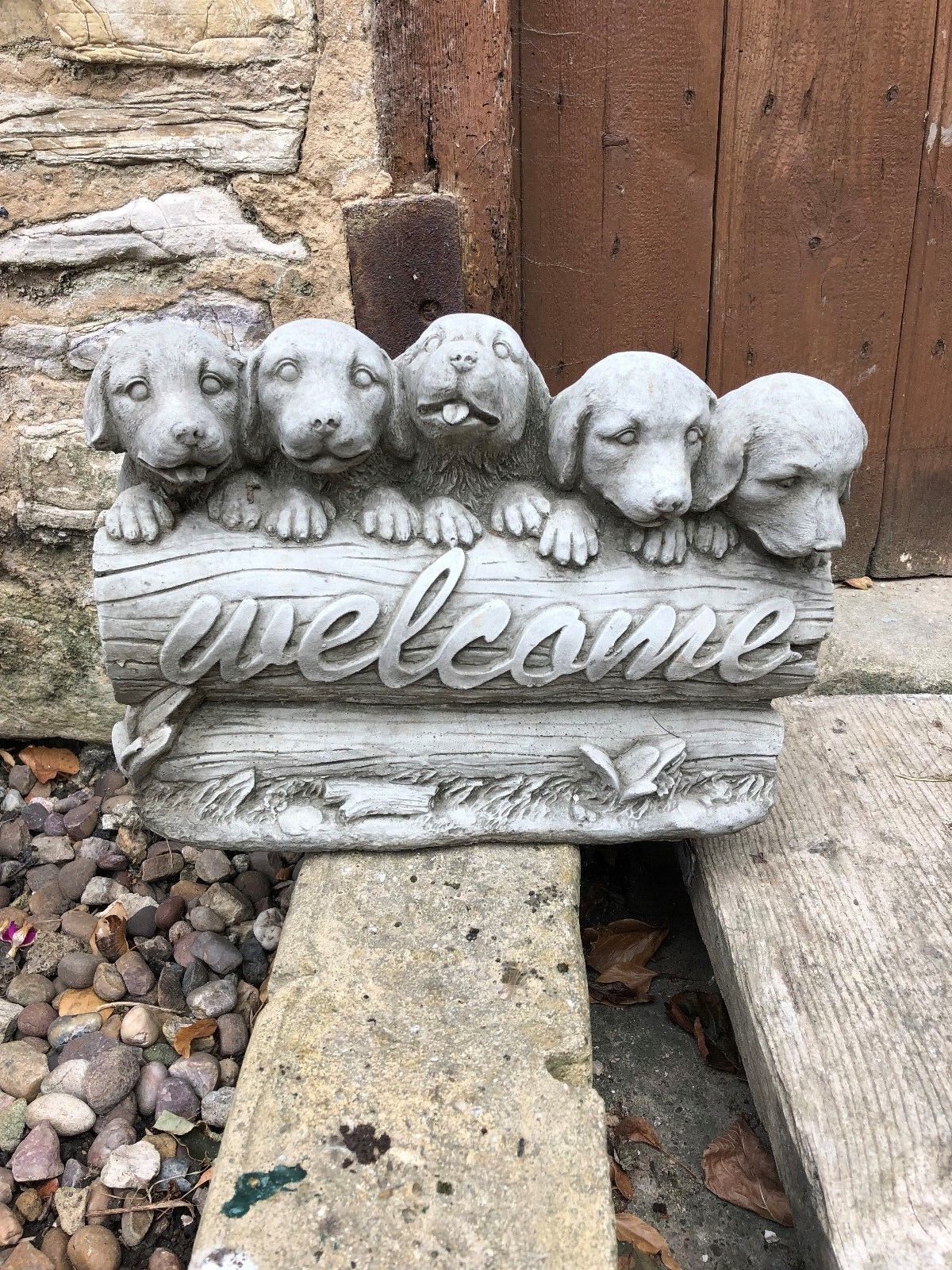 Durable antique-finish stone garden sculpture of puppies on a welcome sign, perfect for patios, porches, or flowerbeds.