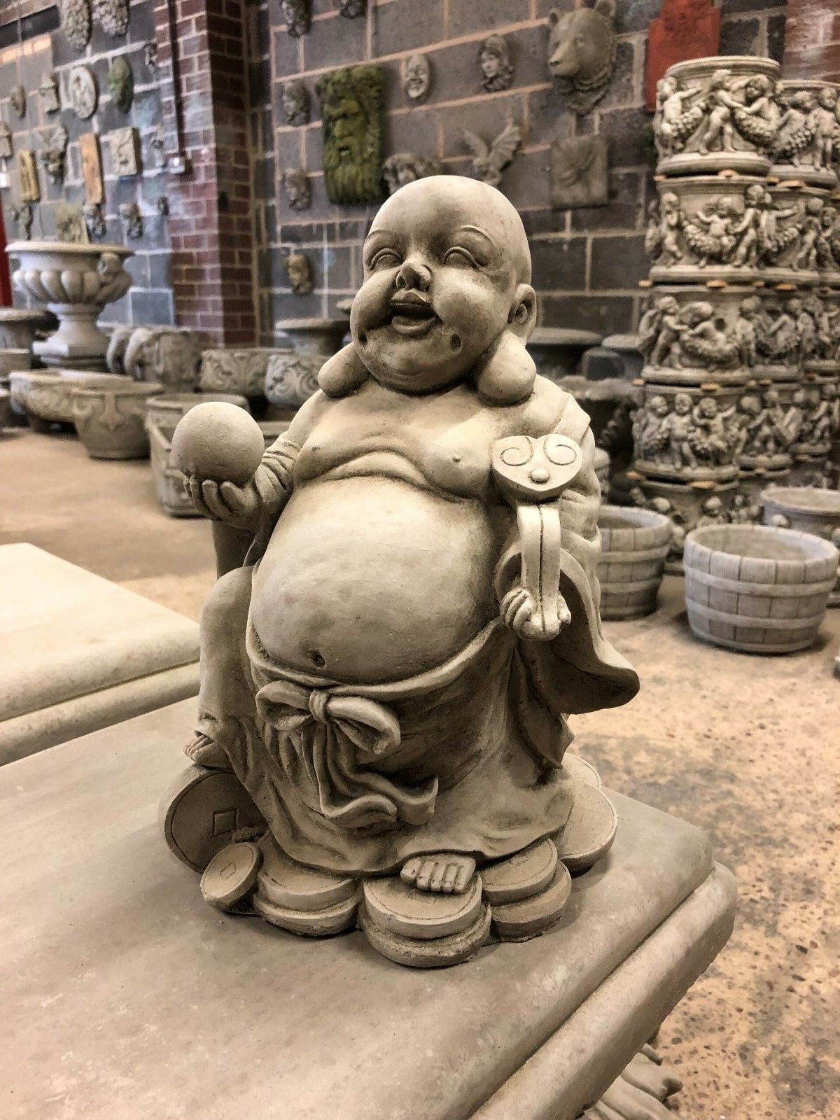 Stone Wealth Buddha Garden Statue seated on coins, symbolizing prosperity, perfect for garden or patio ornamentation.