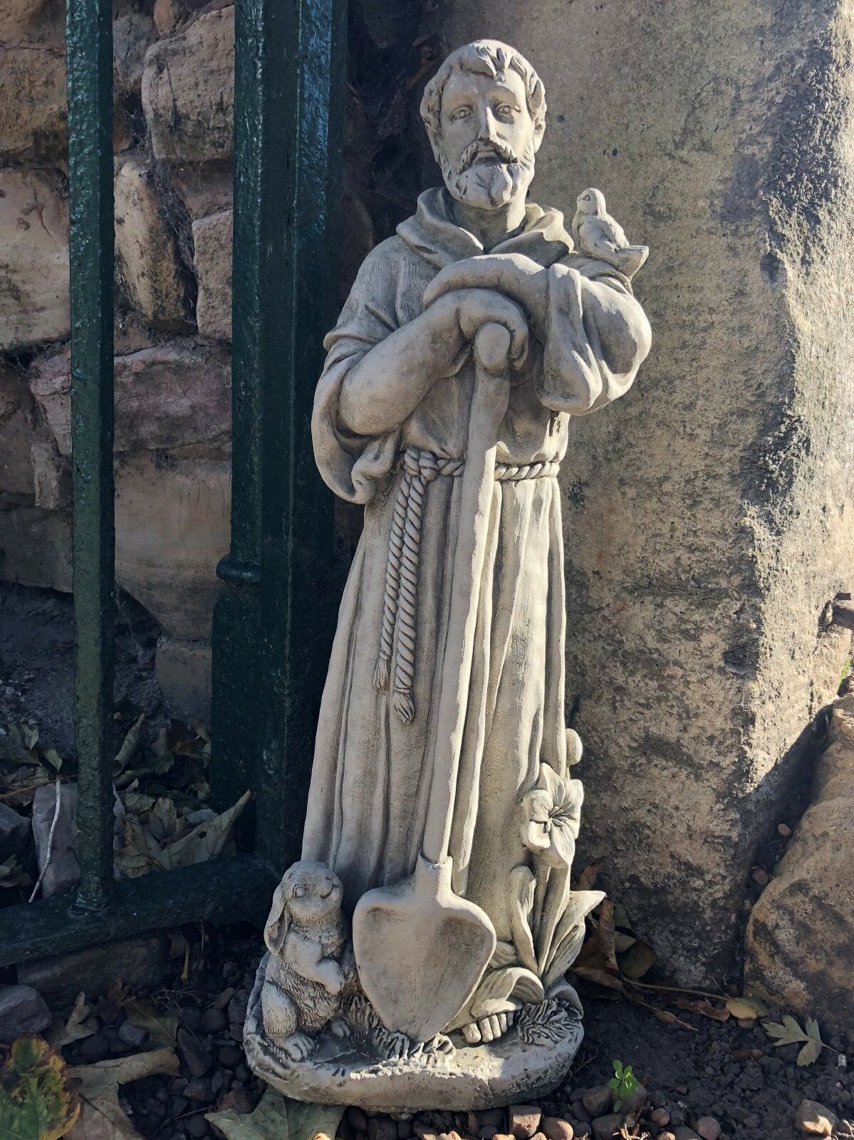 Detailed St Francis garden statue in stone with shovel and animal figures. Weather-resistant sculpture for lawns or religious garden spaces.