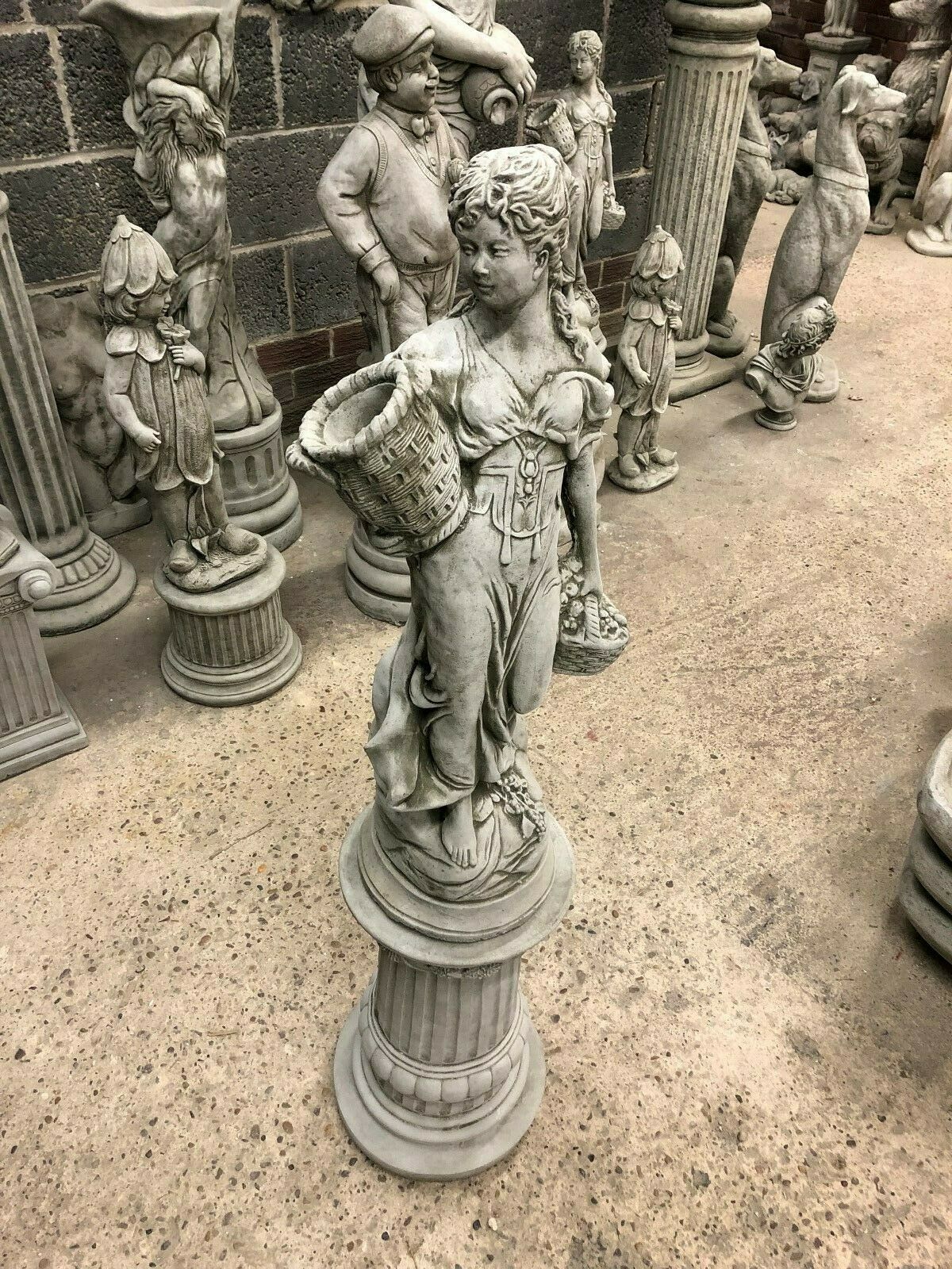 Elegant Stone Roman Lady Garden Statue on limestone plinth, surrounded by other classical figures, perfect for outdoor decor.