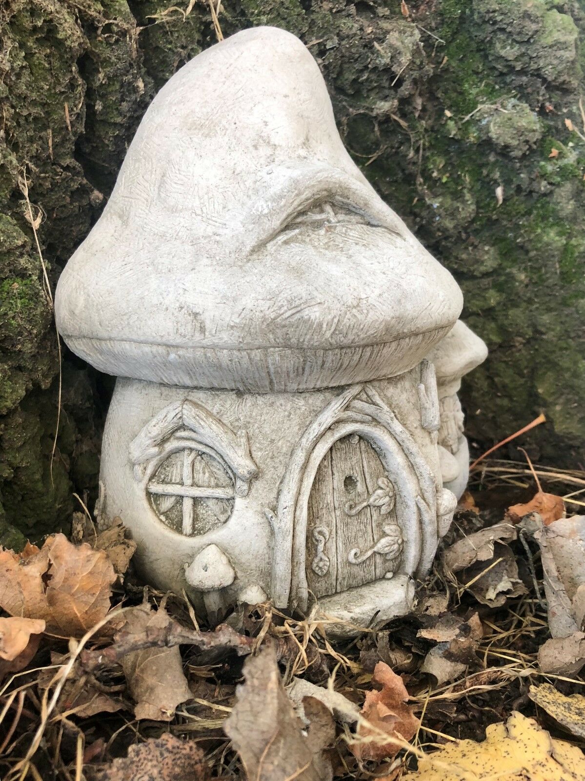 Angled view of Fairy Toadstool Garden Ornament - Stone House with rustic door and whimsical design for garden sculpture lovers.