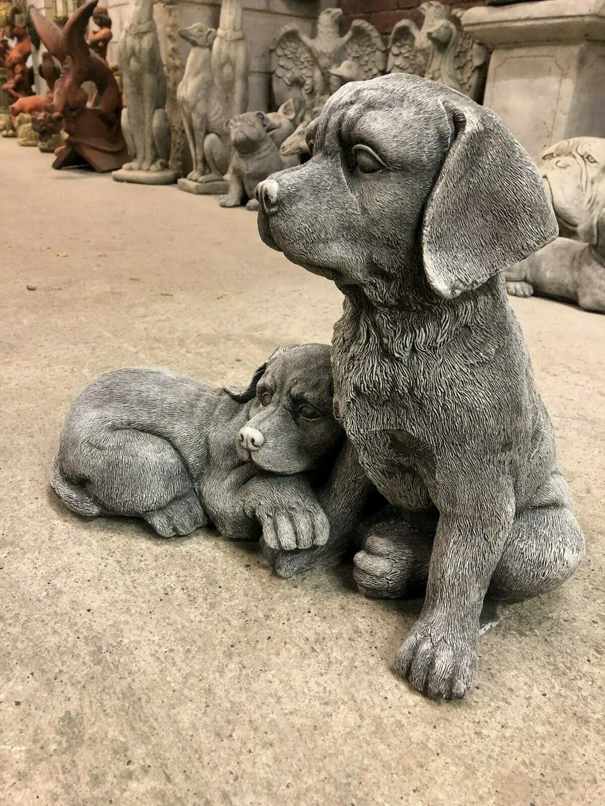 Detailed stone Labrador dog sculptures showing a seated and resting puppy, designed for outdoor garden or porch decoration.