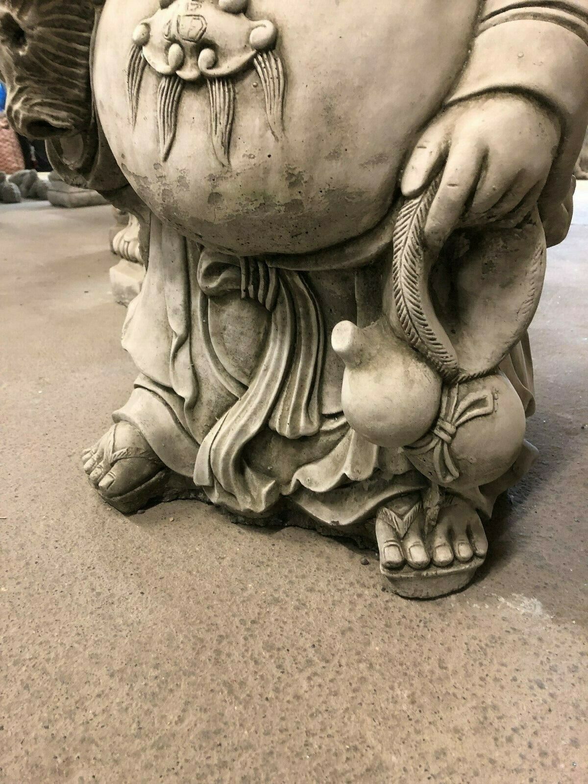 Foot detail of Laughing Buddha Statue holding gourd, emphasizing the solid stone build and symbolic fortune elements.