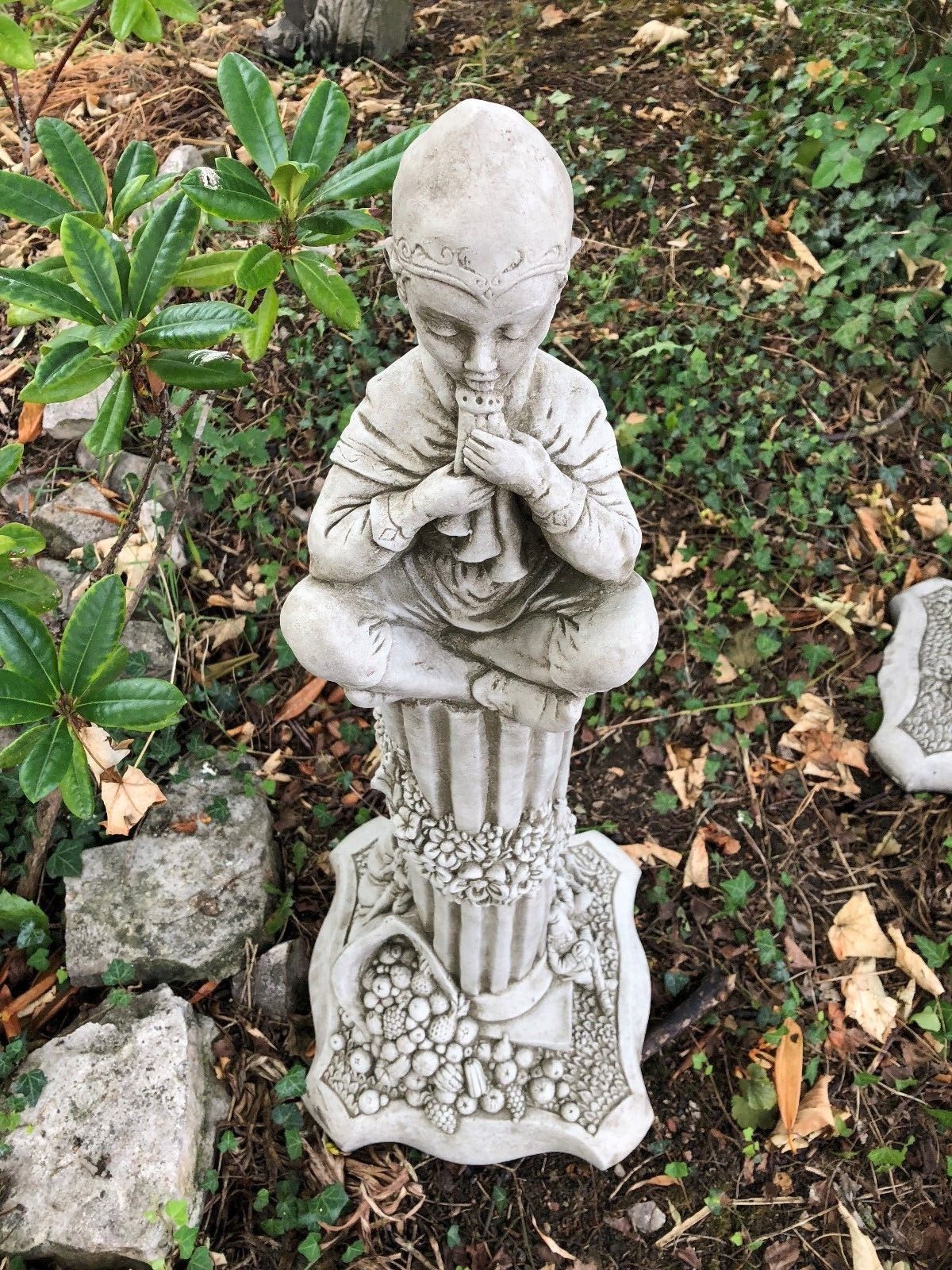 Summer-themed stone statue of a child playing a flute, seated on a floral pedestal from the Stunning Stone Garden Statues collection.
