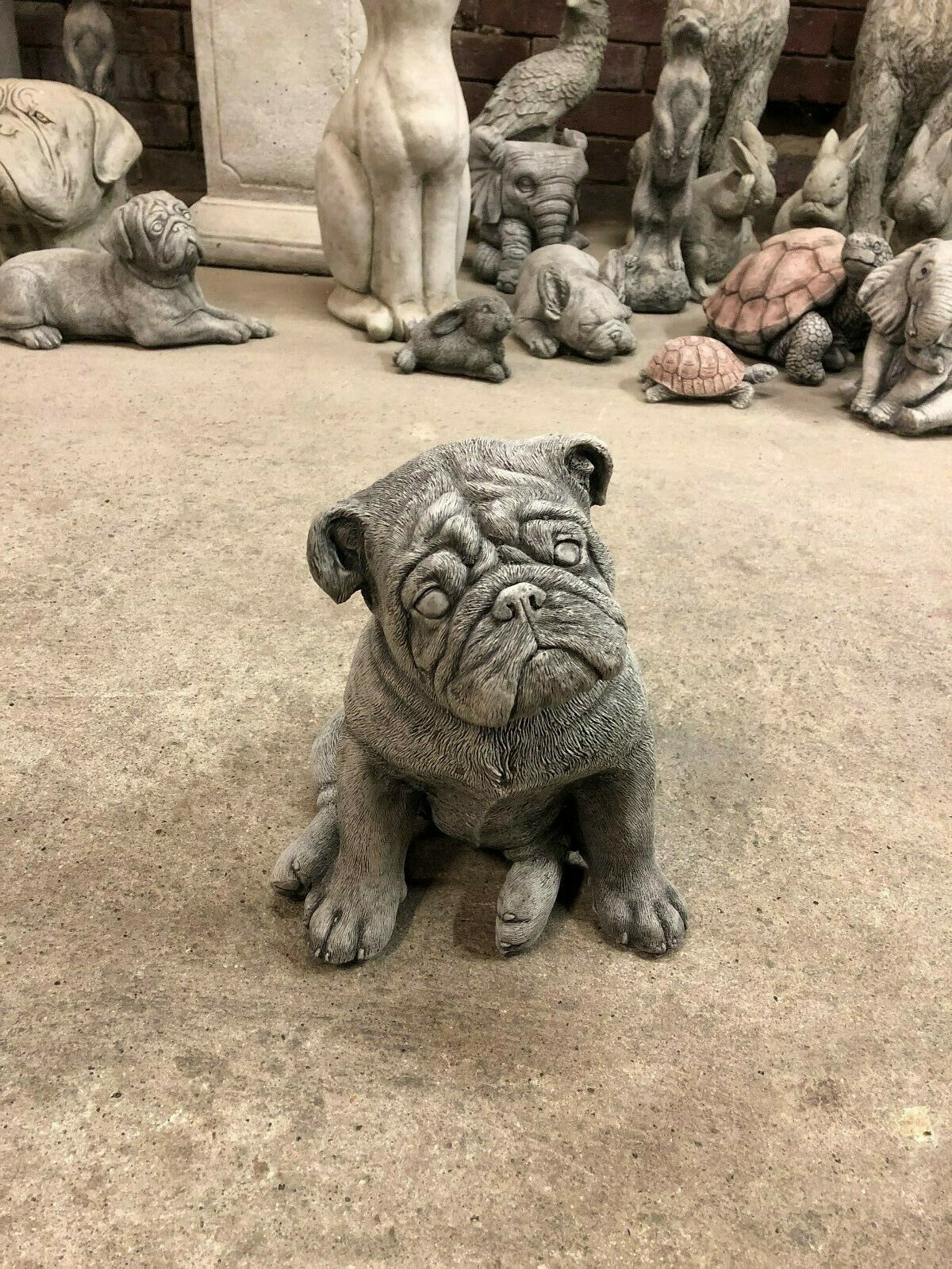 Front view of the Stone British Bulldog Puppy Statue with expressive face and lifelike posture, perfect for lawn or flowerbed decoration.