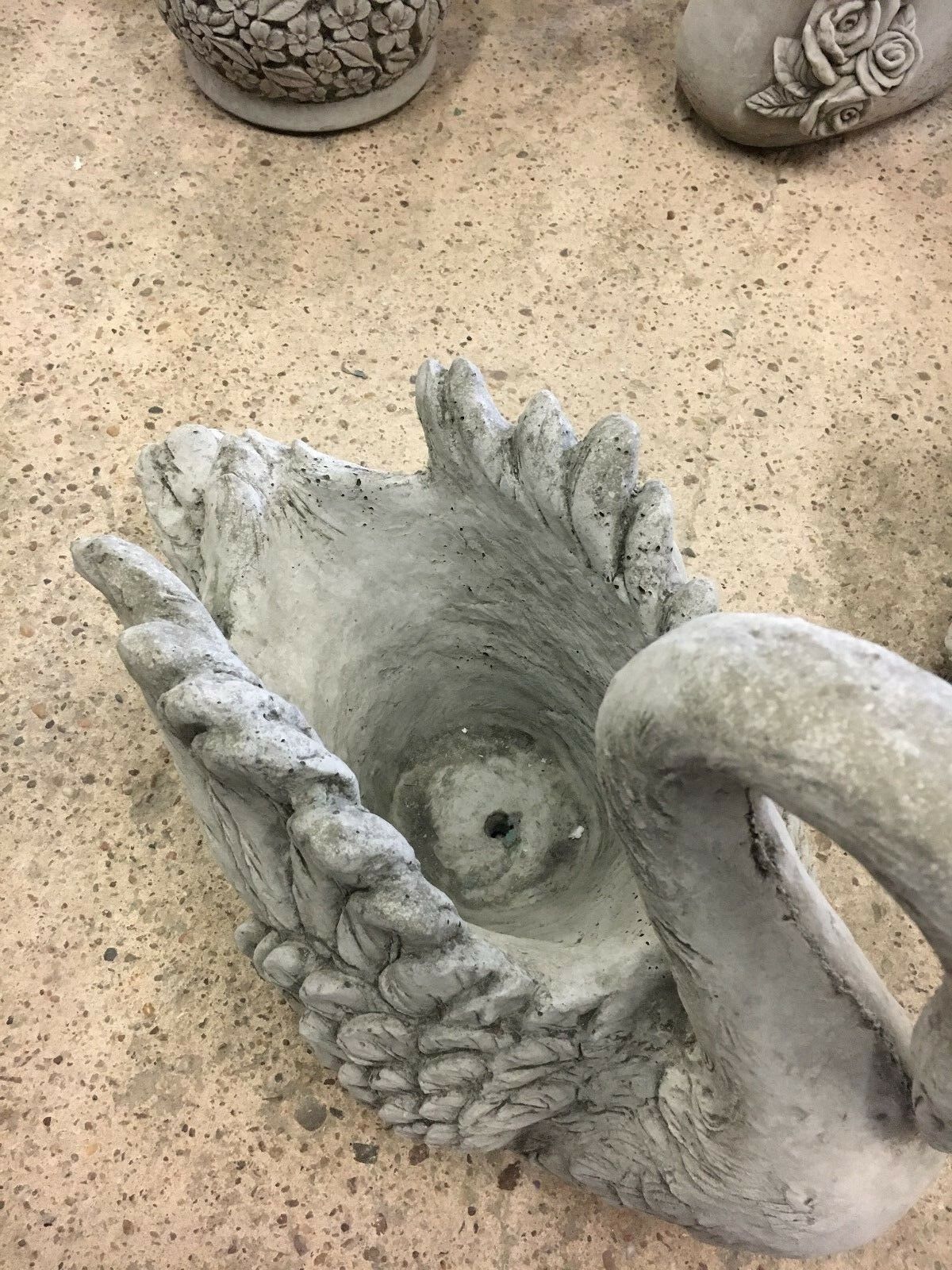 Close-up of interior of stone swan planter highlighting central drainage hole, ideal for preventing water buildup in garden settings.