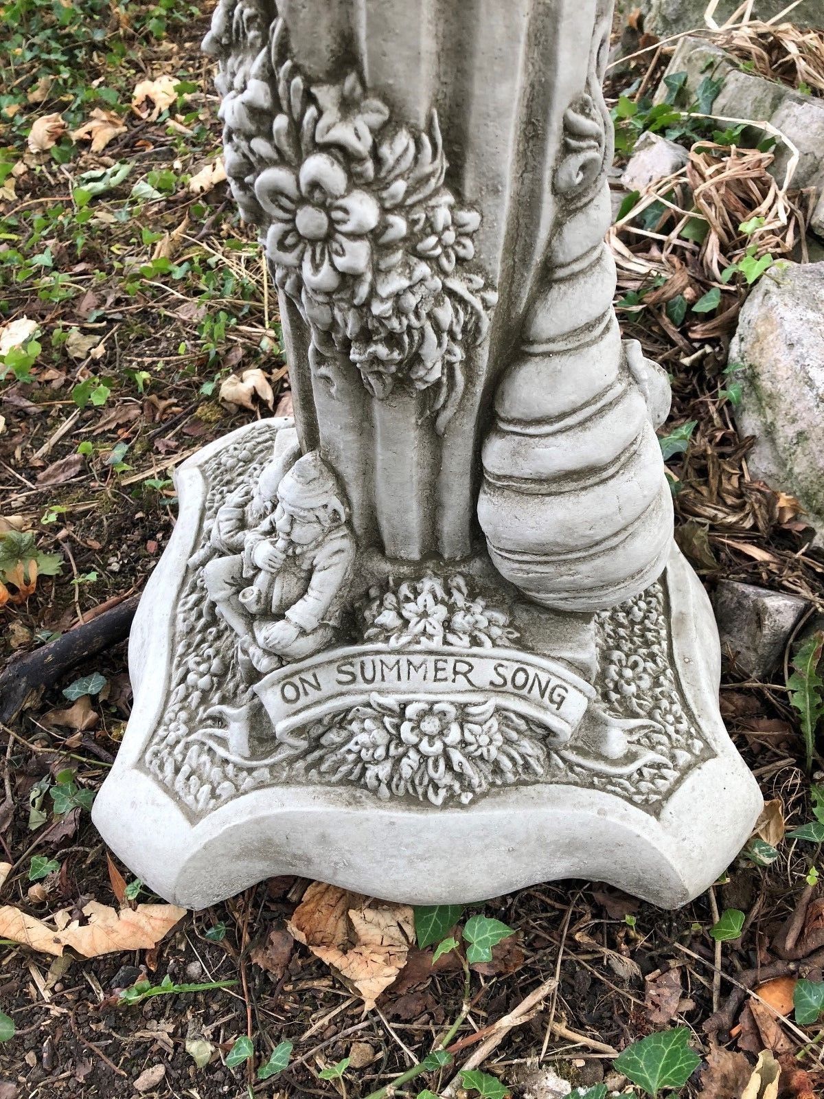 Detail of Summer statue base from Four Seasons Garden Statues, featuring floral carvings and the phrase 'On Summer Song'.