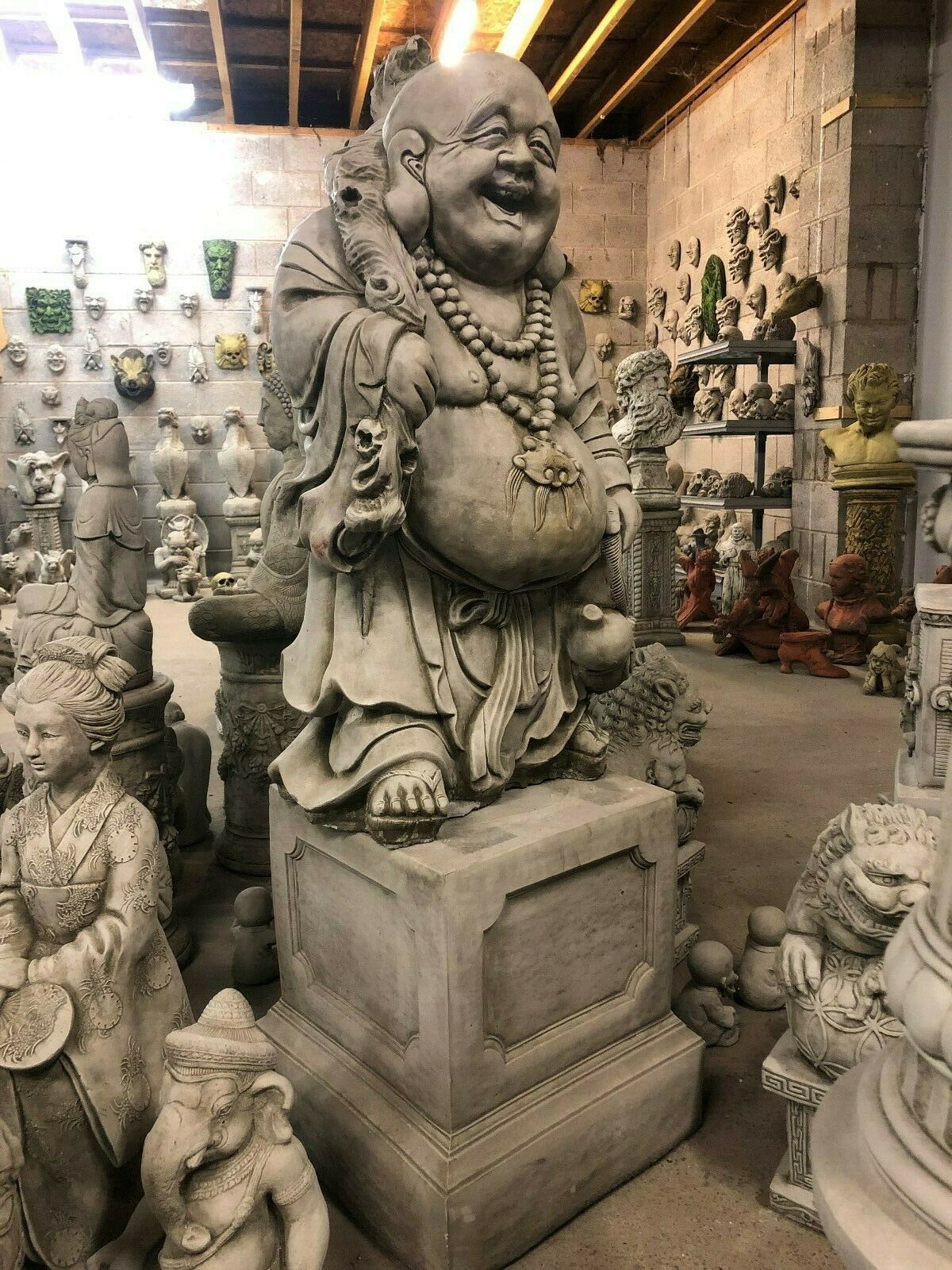Stone Laughing Buddha Statue elevated on a plinth, perfect for indoor or garden fortune decor with a commanding presence.