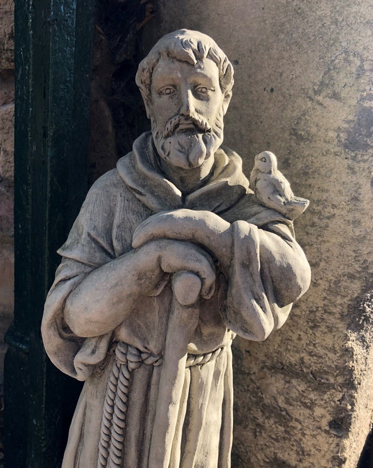 Close-up of St Francis stone statue holding a bird, showcasing fine craftsmanship. Ideal for Christian-themed garden decor.
