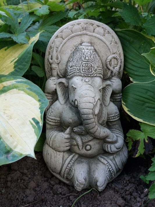Ganesh Garden Ornament - Small Stone statue nestled among green hosta plants. Weatherproof and ideal for spiritual garden decor.