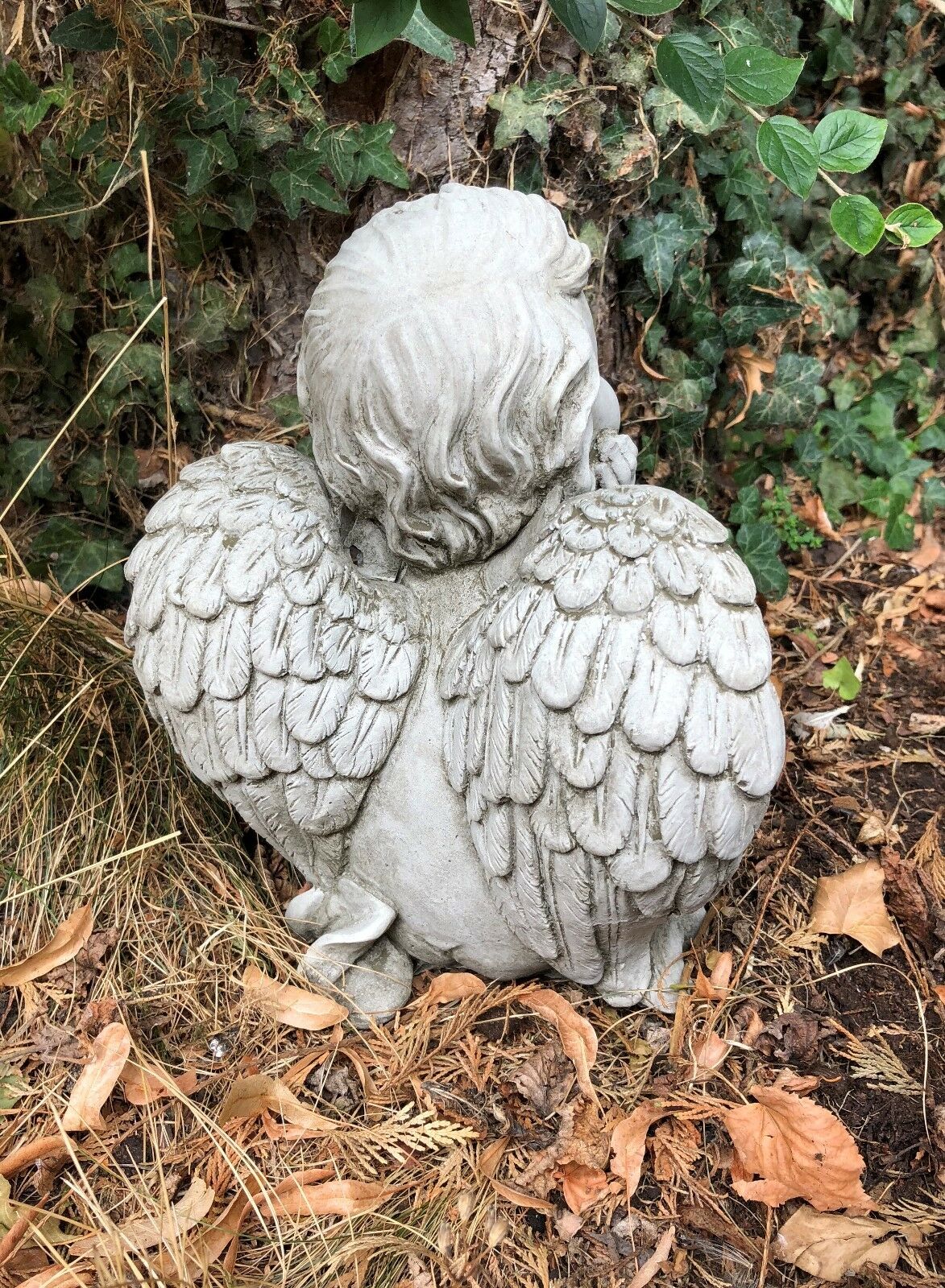 Rear view of stone cherub with textured wings. Durable limestone garden ornament for outdoor spiritual or decorative use.