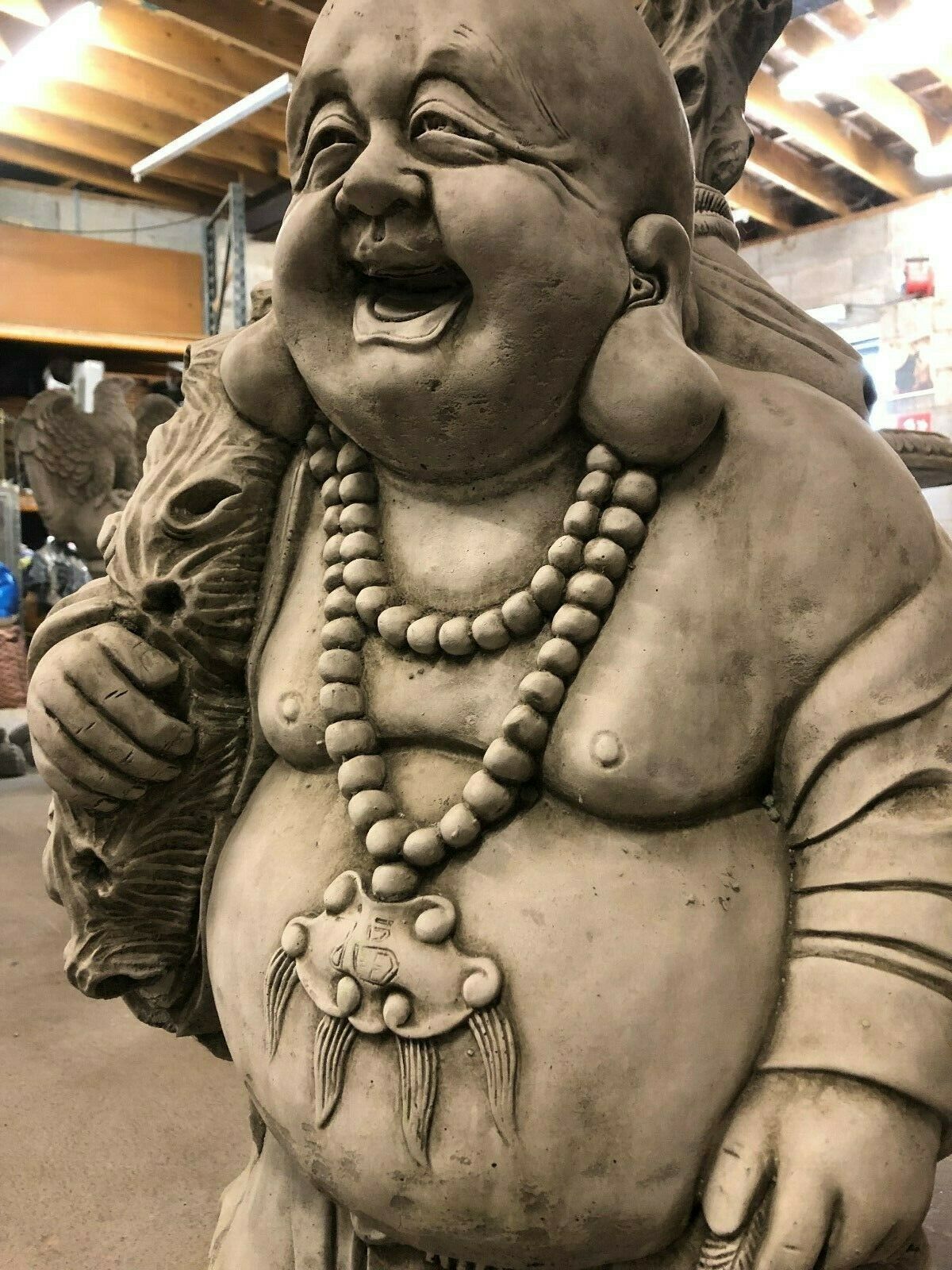 Close-up of Laughing Buddha’s joyful face and necklace, highlighting the detailed stonework and symbolism of happiness and wealth.