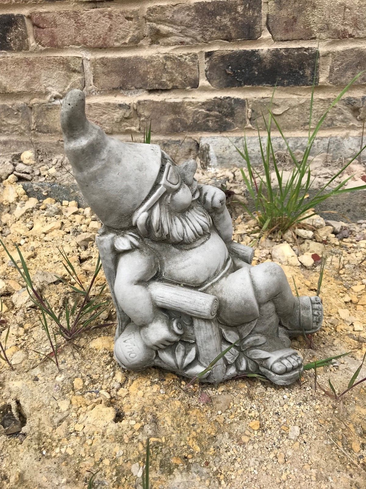 Side view of Stone Garden Gnome Ornament in a relaxed pose, perfect for patios or flowerbeds to add charm to your outdoor space.