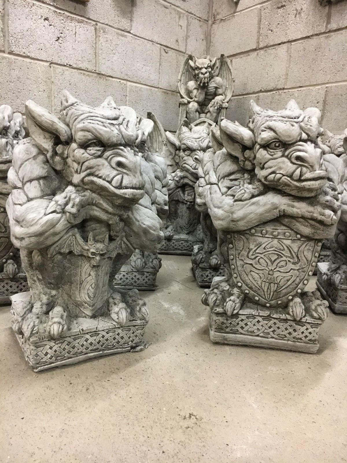 Stone sword shield gargoyle statues with fierce expressions and intricate detailing, ideal for enhancing garden décor with a medieval fantasy theme.