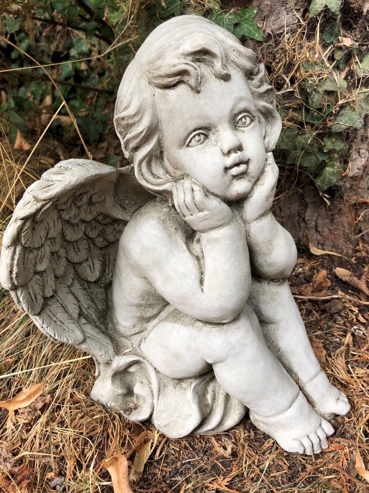 Front view of stone baby angel with expressive eyes and feathered wings. Ideal for enhancing garden aesthetics or memorial spaces.