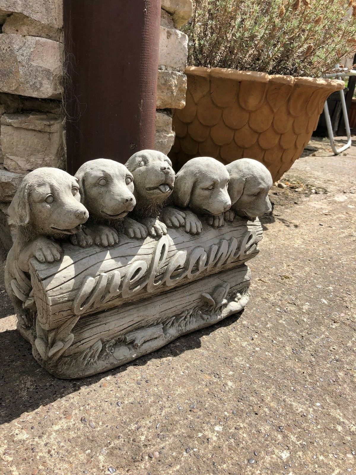 Side view of stone welcome puppies garden ornament, highlighting lifelike puppy expressions and textured log design.