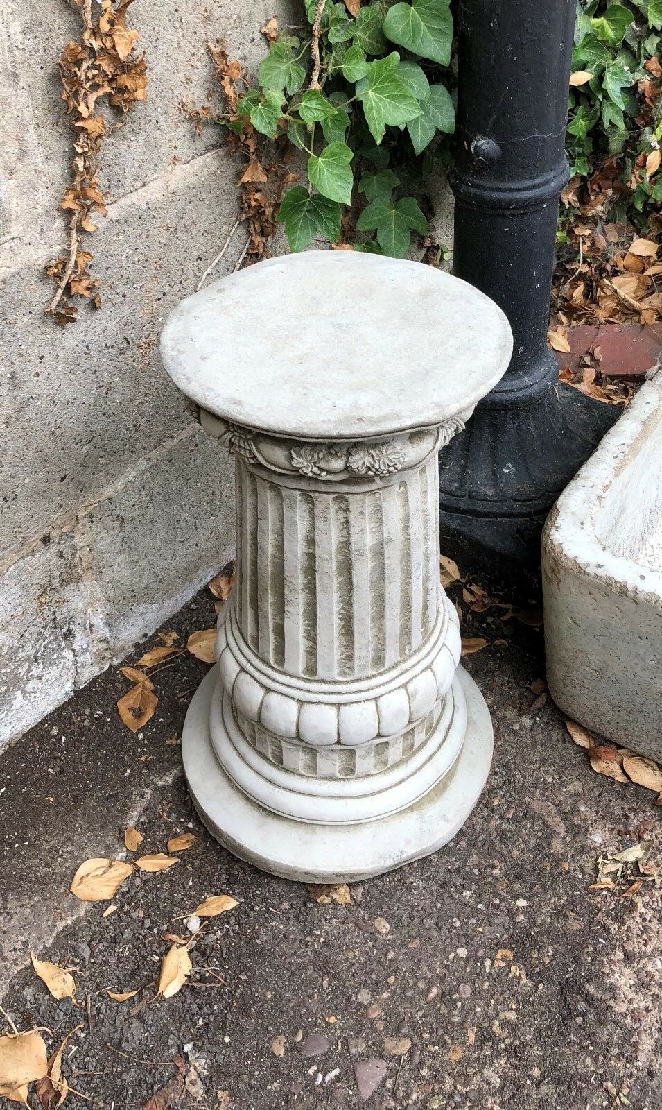 Ornate stone pedestal with fluted column design, ideal base for garden statues or decorative outdoor sculptures in classic settings.