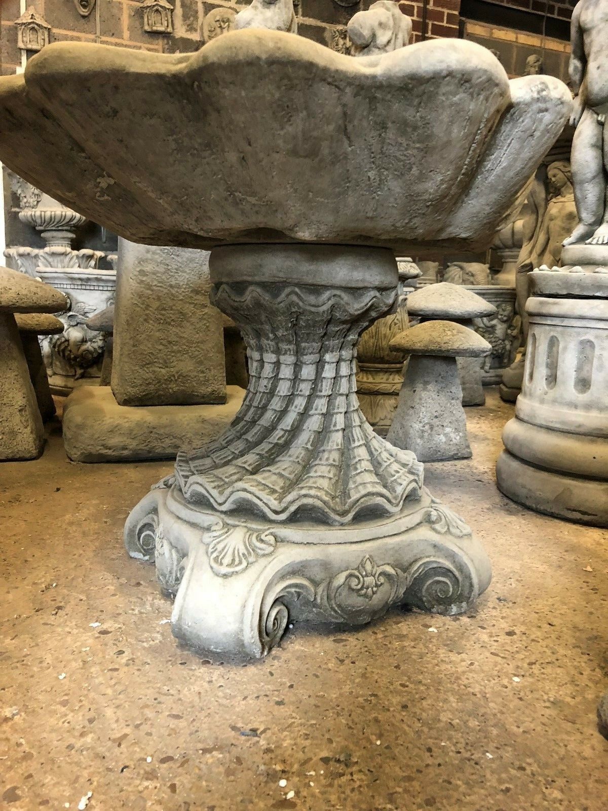 Side angle of the Stone Shell Bird Bath showing its sculpted base and shell bowl, perfect for classic garden decoration.