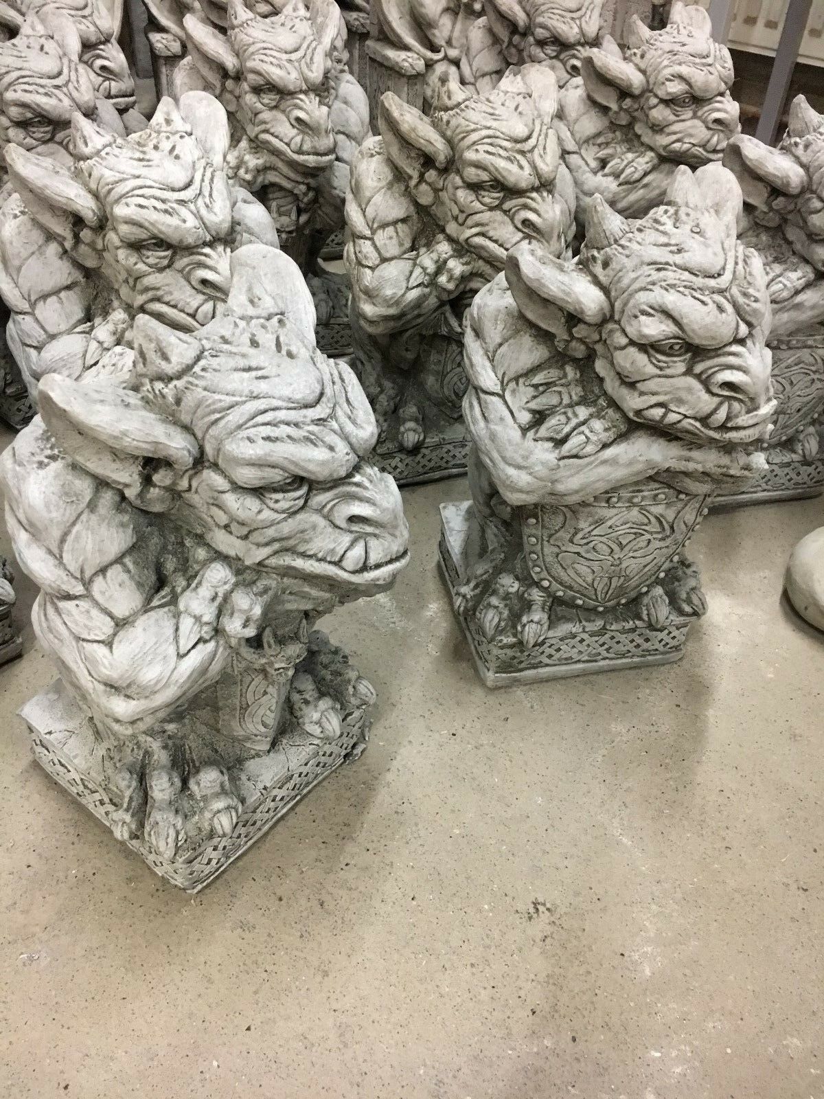 Detailed stone gargoyle garden statues with shield and sword motifs, perfect for fantasy-themed outdoor decoration and weather resistance.