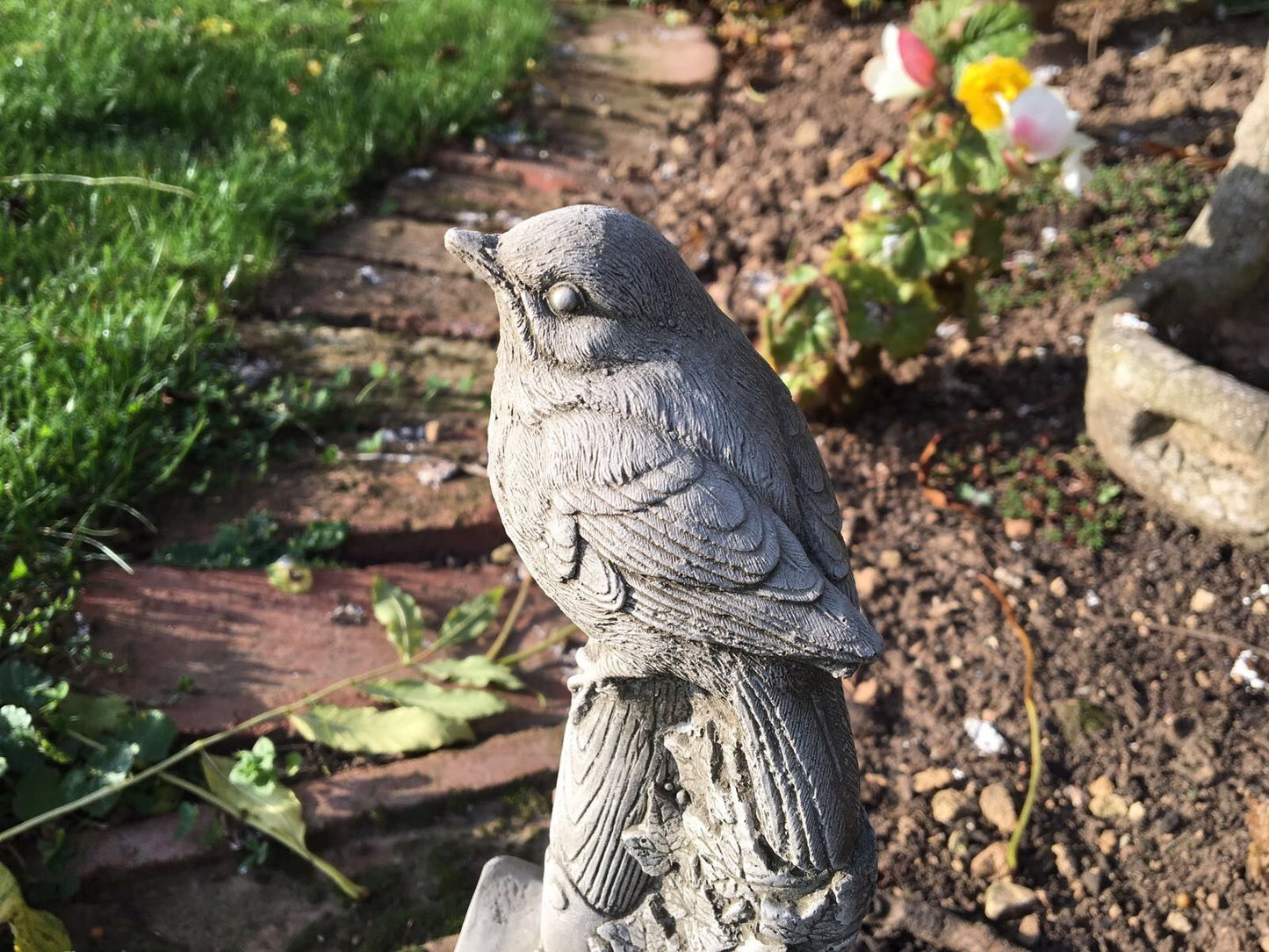 Close-up of Stone Bird Garden Ornament perched on a spade handle. Weather-resistant limestone with intricate feather detailing.