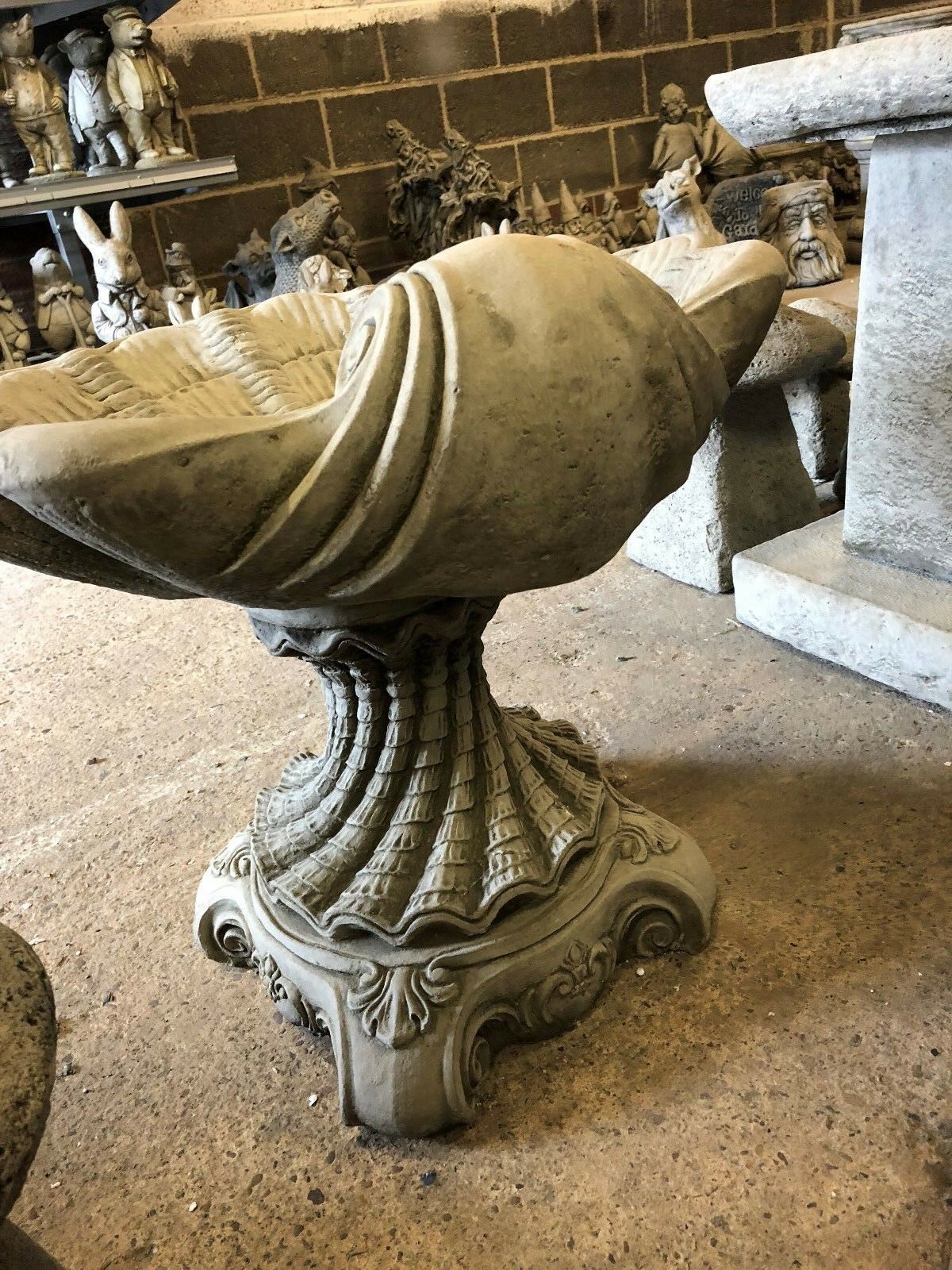 Profile view of the Stone Shell Bird Bath with spiral shell detail, showcasing its artistic design and durable stone structure.
