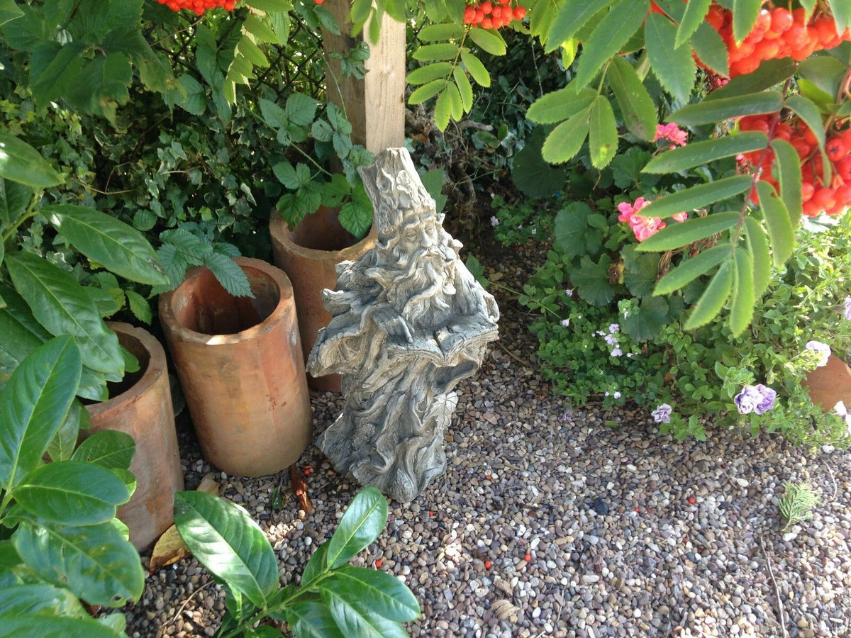 Detailed Wizard Garden Statue in a flowerbed corner, perfect for whimsical garden decor with free UK delivery.