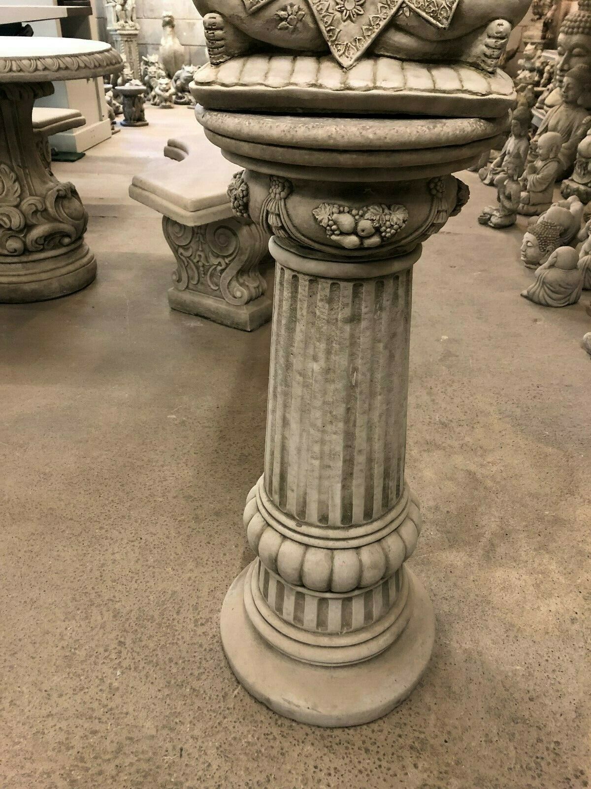 Mid-section of the fluted pedestal supporting the Stone Seated Buddha Statue, adorned with carved garlands and stone texture.