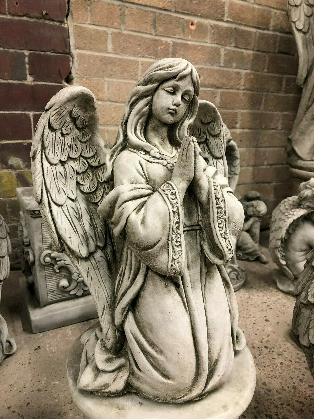 Close-up of Durable Stone Praying Angel Statue with intricate robe and wing details. Antique finish enhances its charm for garden ornamentation.