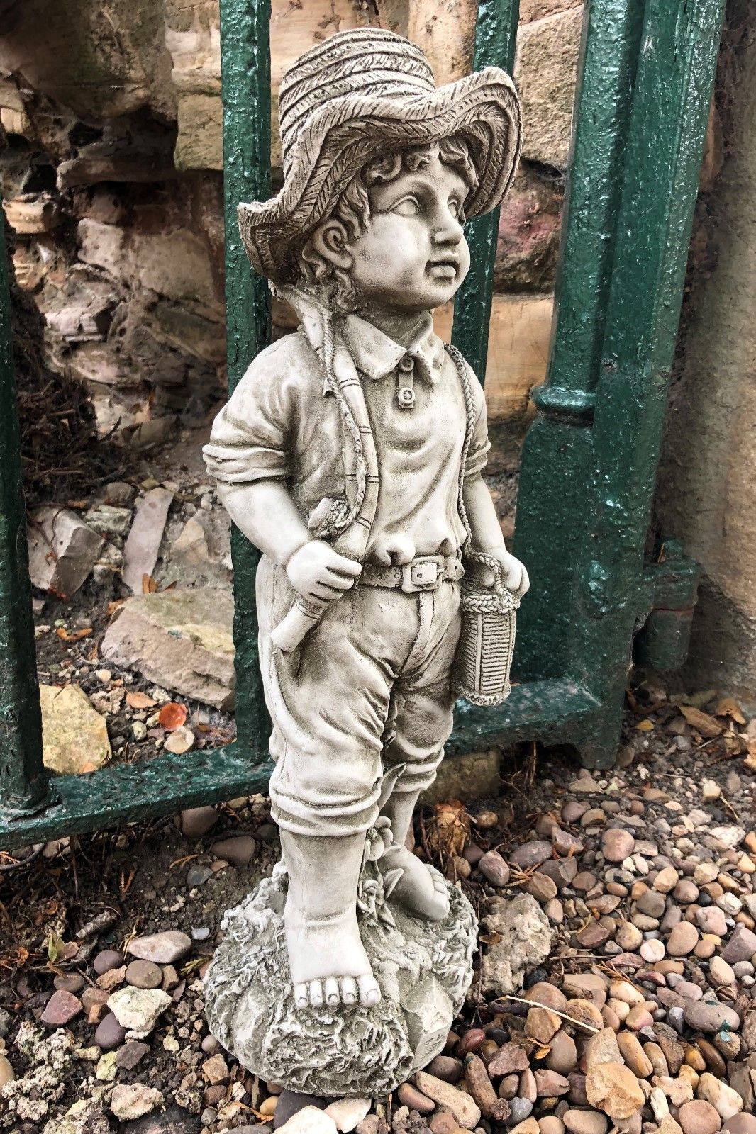Angled view of fisher boy garden ornament with detailed stone texture, barefoot and holding a basket, perfect for patio or lawn decor.