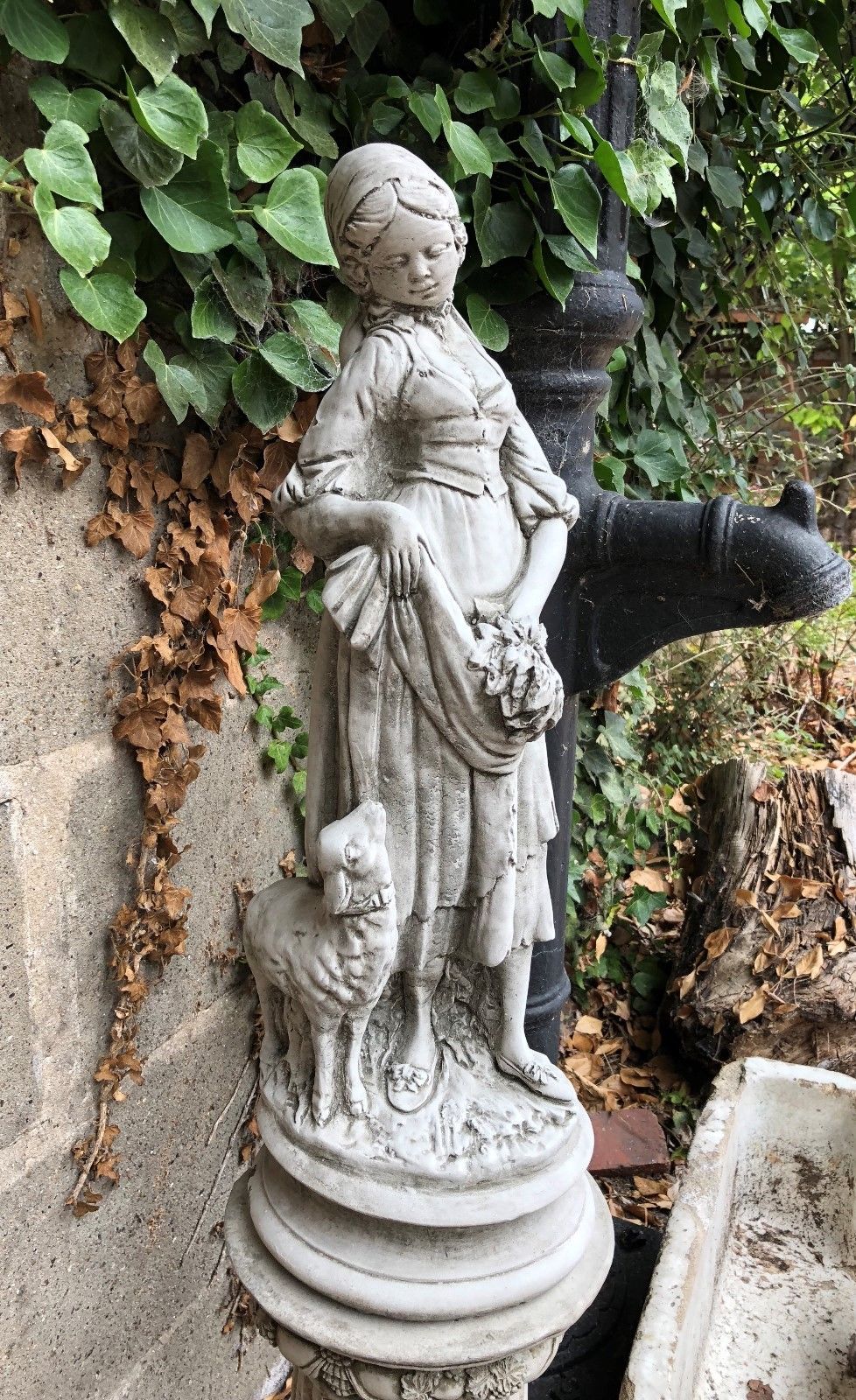 Stone Garden Shepherdess Statue with lamb on pedestal, highlighting elegant antique finish and solid stone construction for outdoor use.