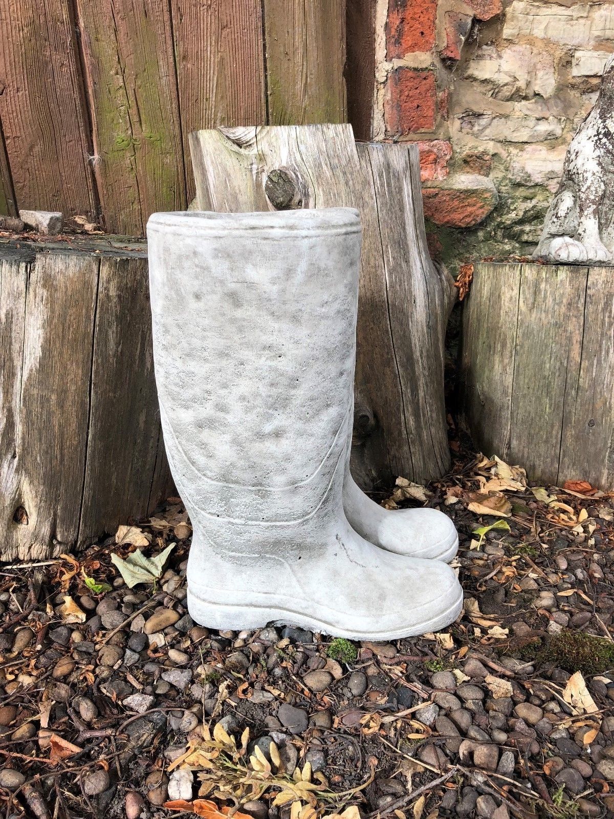 Durable Stone Wellington Boots Planter for outdoor gardens, featuring weather-resistant limestone and antique texture near wooden stumps.