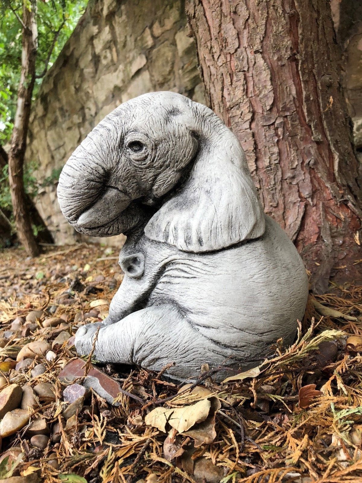 Single stone baby elephant ornament sitting under a tree, perfect for enhancing garden beds or patio corners with charming animal decor.