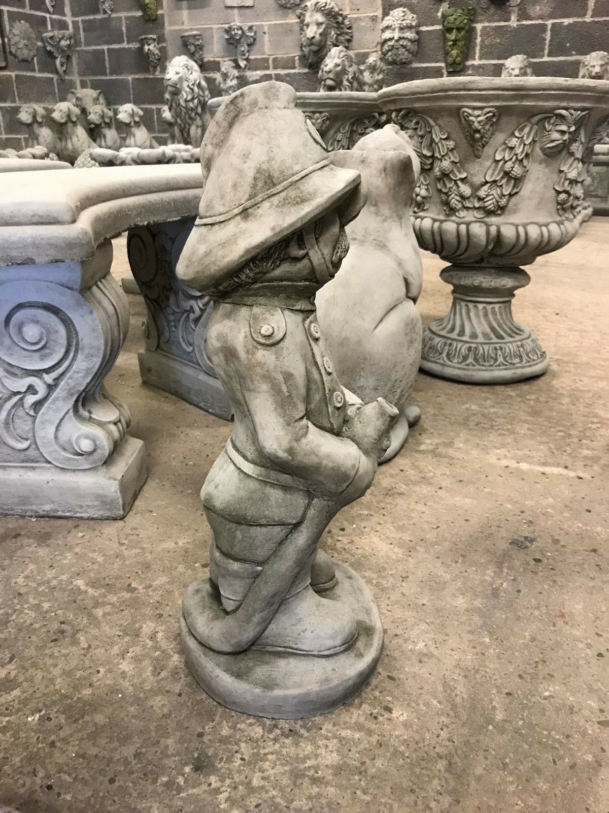 Side view of Stone Fireman Garden Ornament showing sculpted uniform and hose, crafted from heavy limestone for patios, lawns, or flowerbeds.