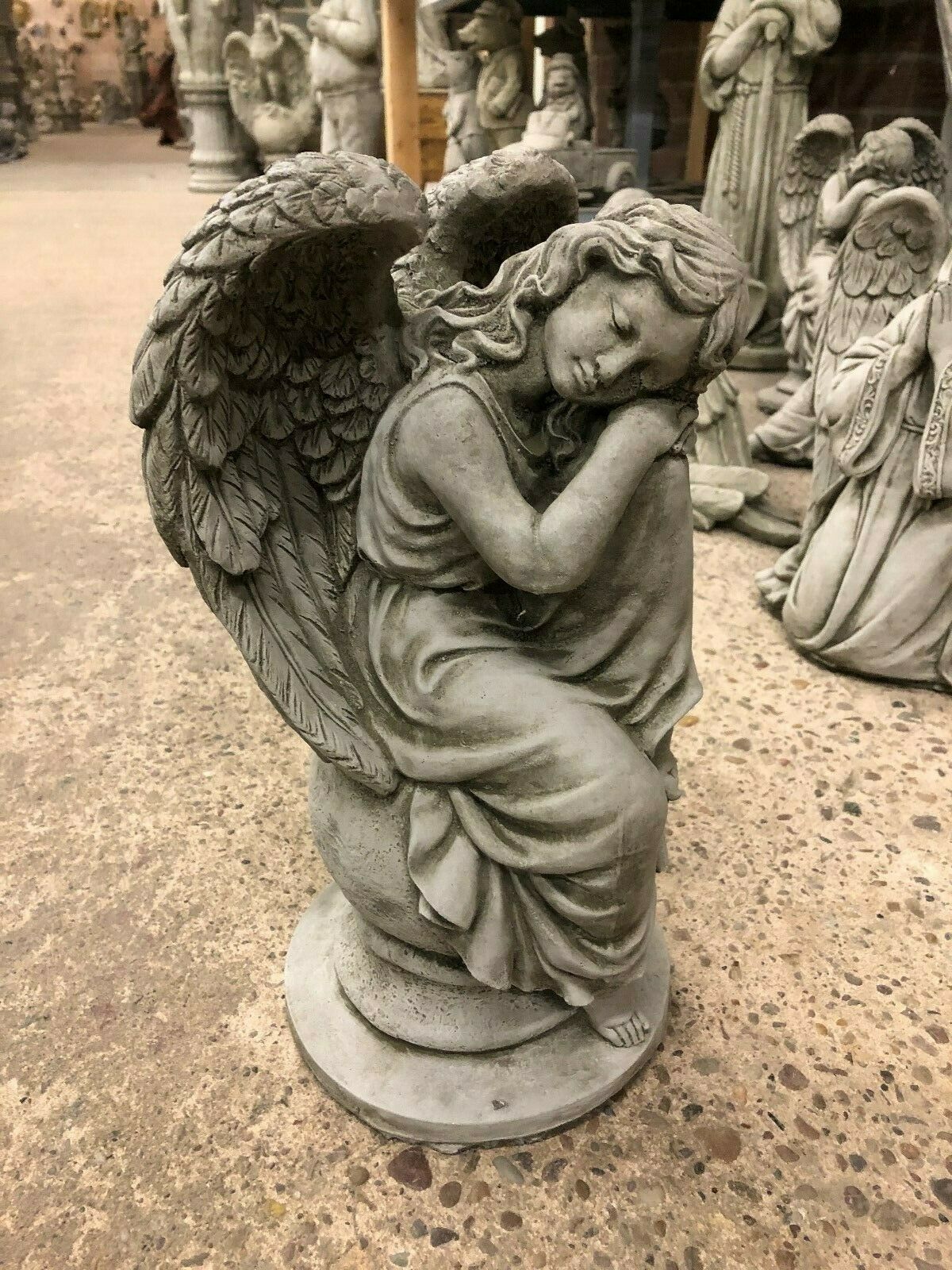 Close-up of Stone Angel Garden Statue resting on a ball, showcasing detailed wings and peaceful expression, made from fine limestone.
