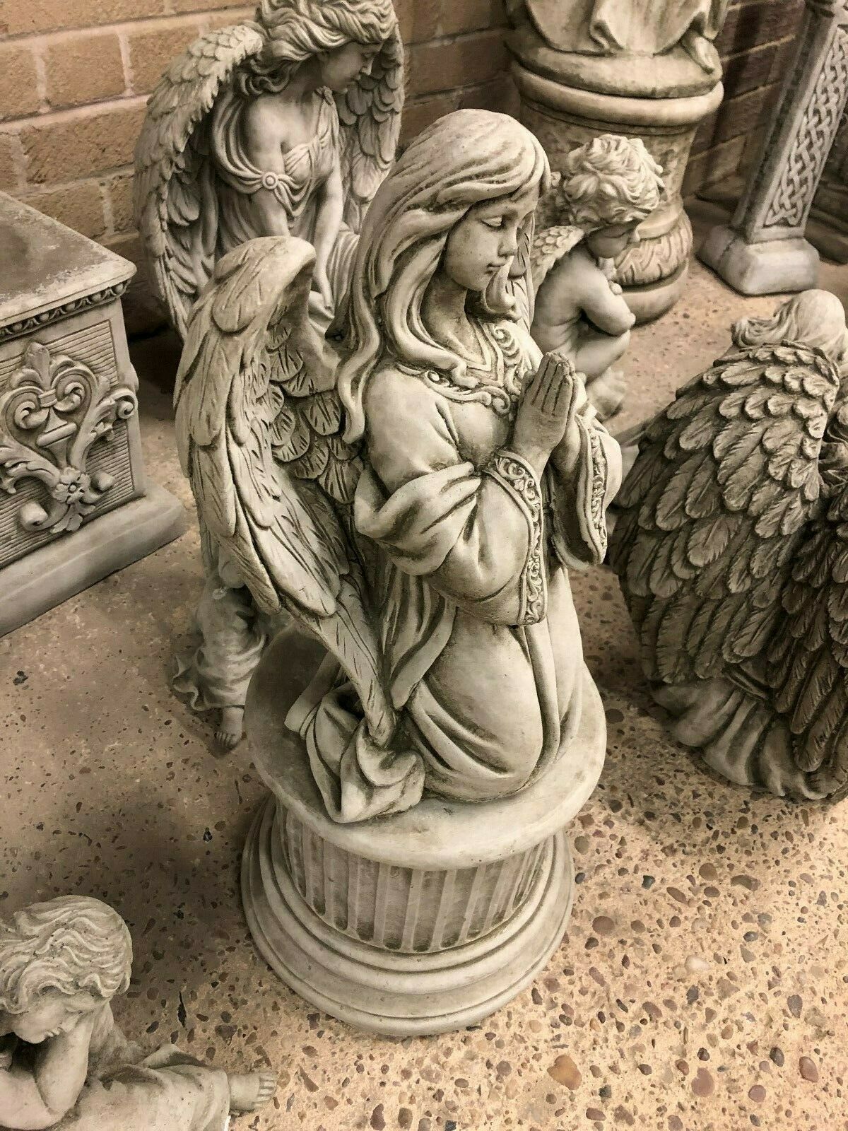 Side view of Durable Stone Praying Angel Statue on pedestal, showcasing detailed wings and serene expression. A timeless garden sculpture piece.