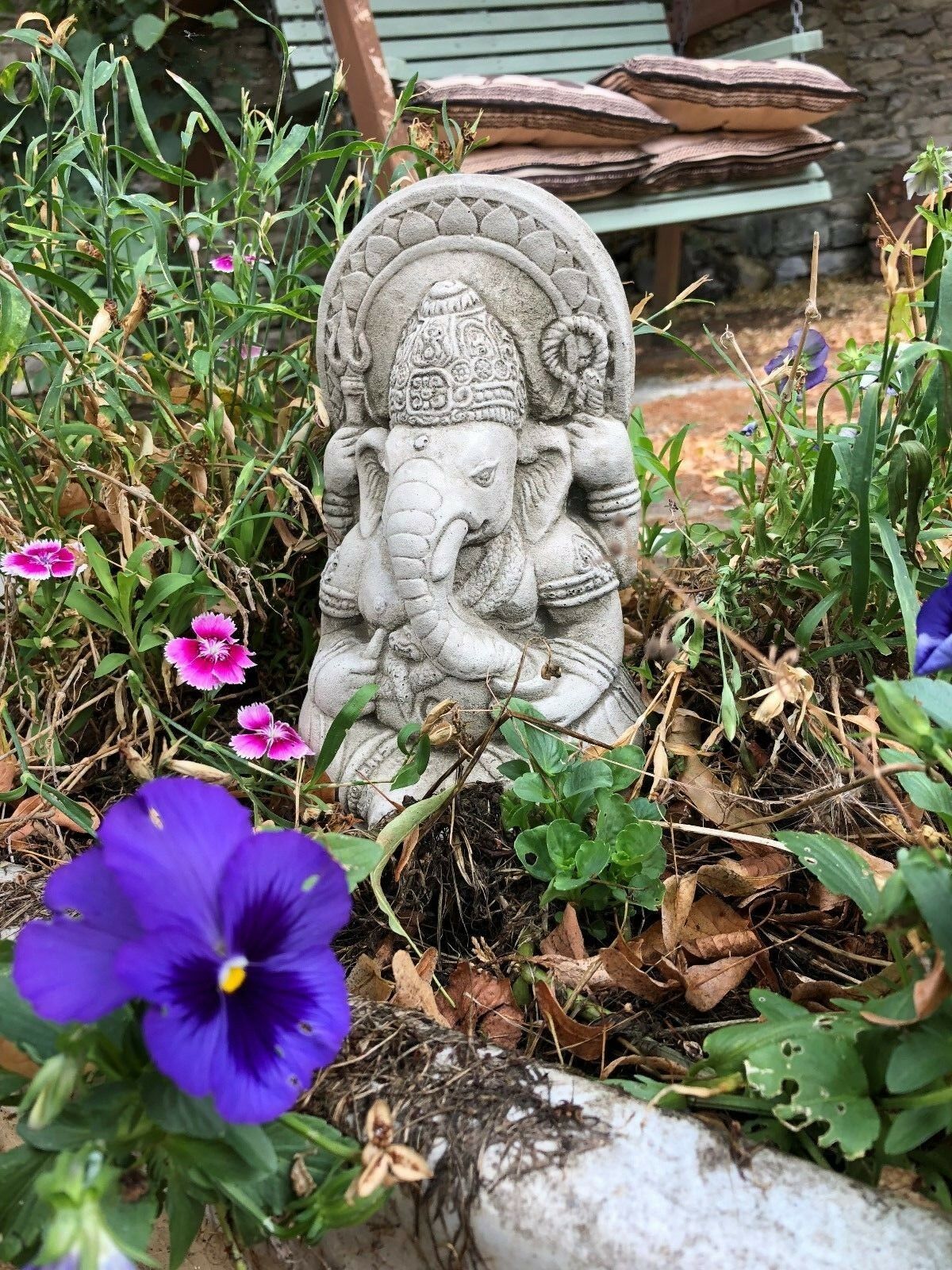 Small Stone Ganesh Garden Ornament surrounded by purple and pink flowers. Weatherproof and perfect for garden spirituality.
