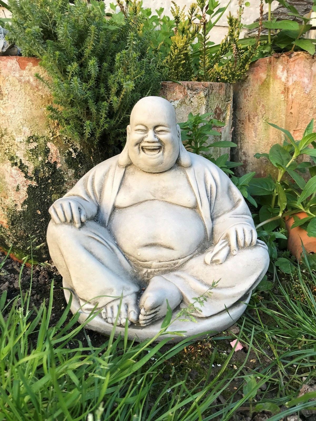 Stone Laughing Buddha Ornament in a lush garden setting, made from durable limestone, ideal for zen garden decor and symbolizing joy and fortune.