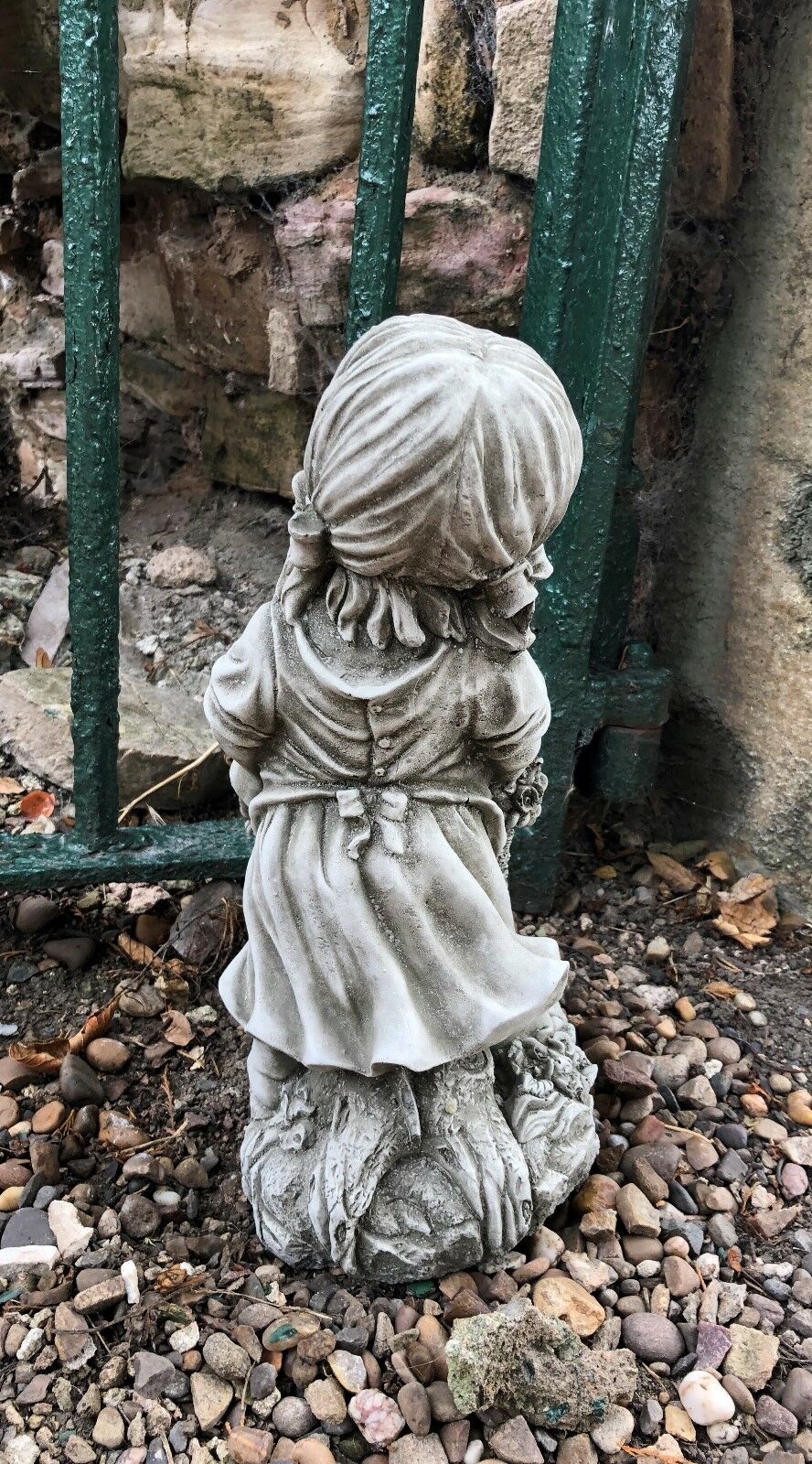 Rear view of basket girl garden ornament showing dress and hair detail, crafted in stone for vintage garden sculpture appeal.