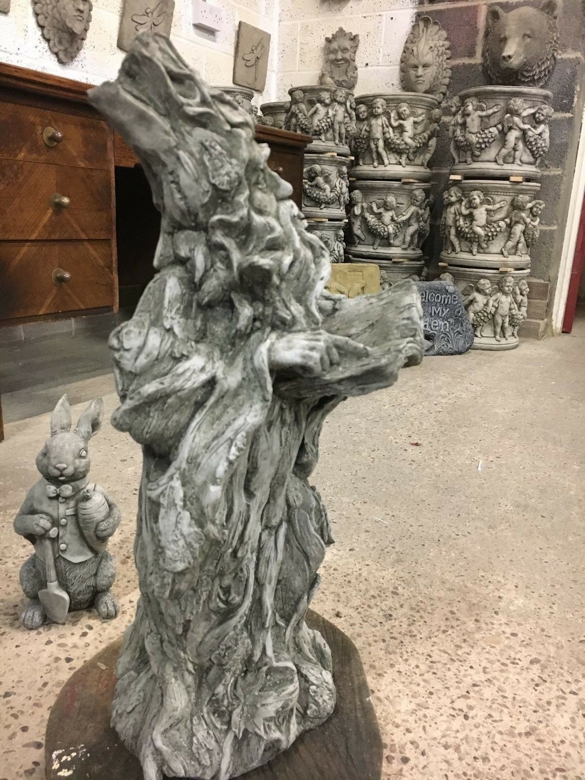 Side-back view of Wizard Garden Statue in showroom, showcasing its flowing robe and rustic stone finish.