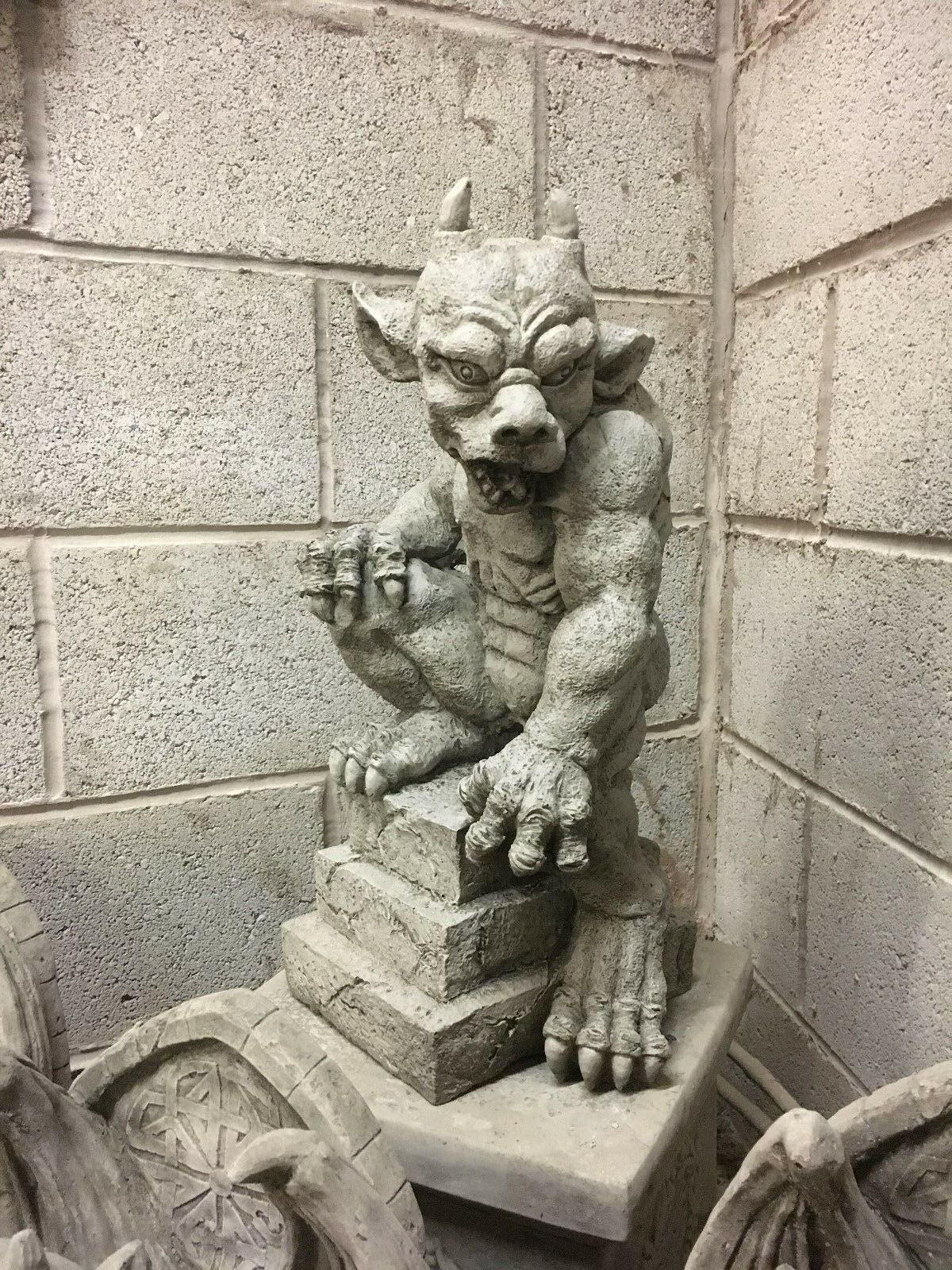Rear view of heavy stone gargoyle statue showing muscular back and textured limestone finish, perfect for garden or patio ornamentation.