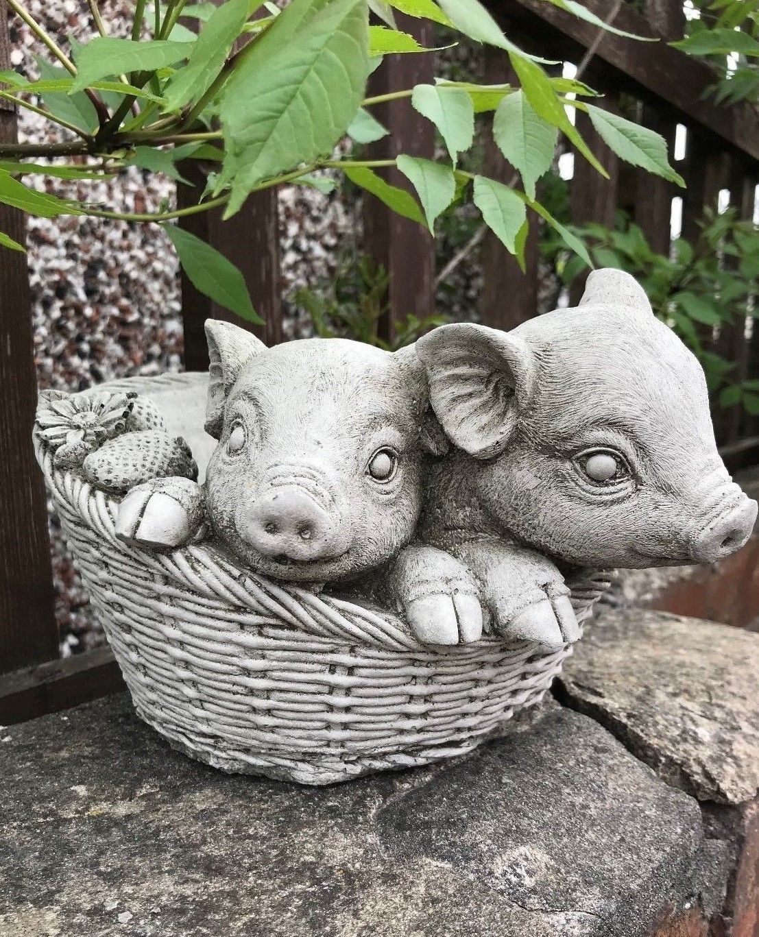 Stone pig planter ornament featuring two piglets in a woven basket design with strawberry and flower details. Durable garden sculpture for outdoor decor.