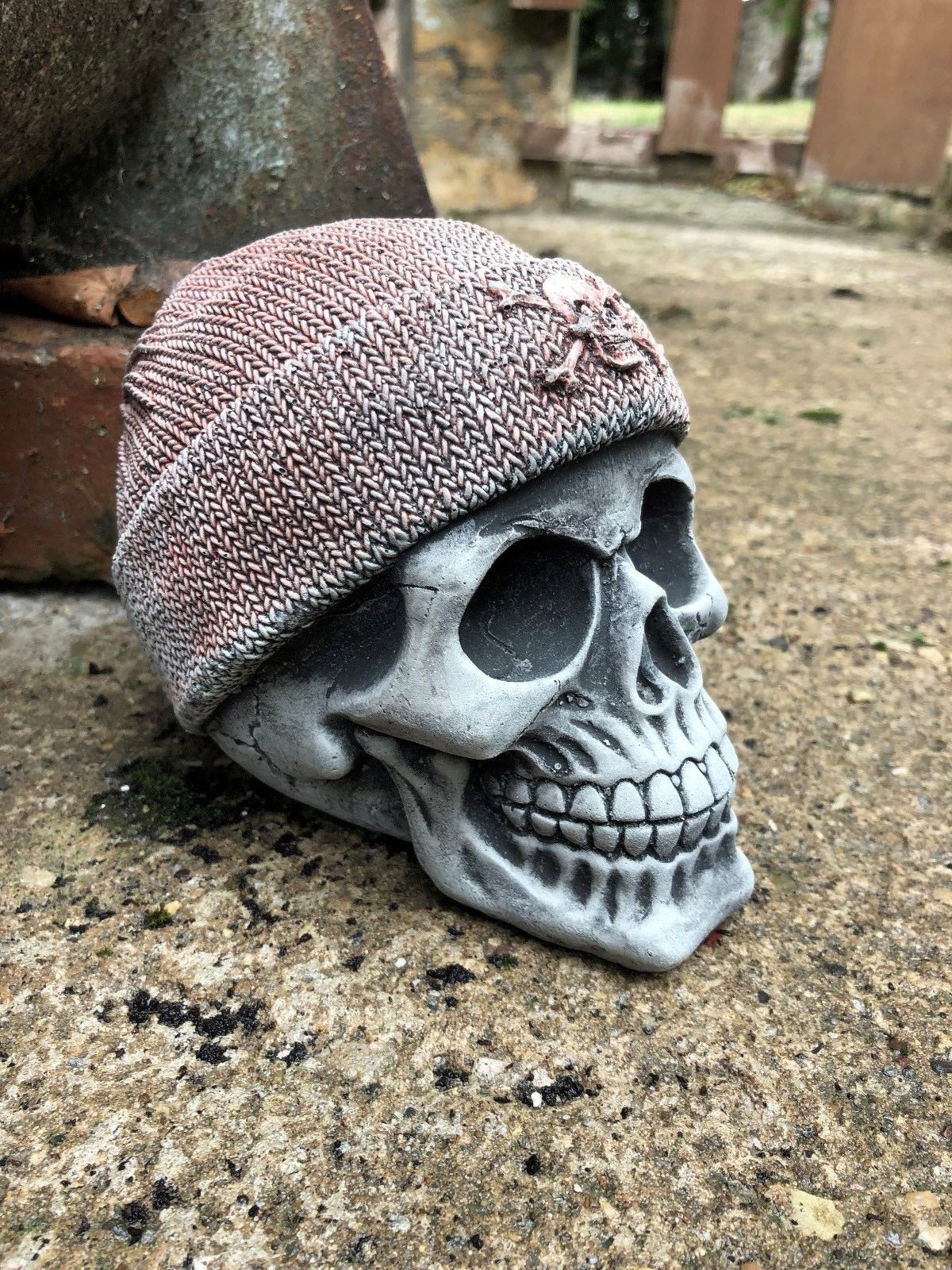 Angled view of Stone Skull Beanie Ornament highlighting its sculpted features and rugged outdoor appeal for unique garden sculpture displays.