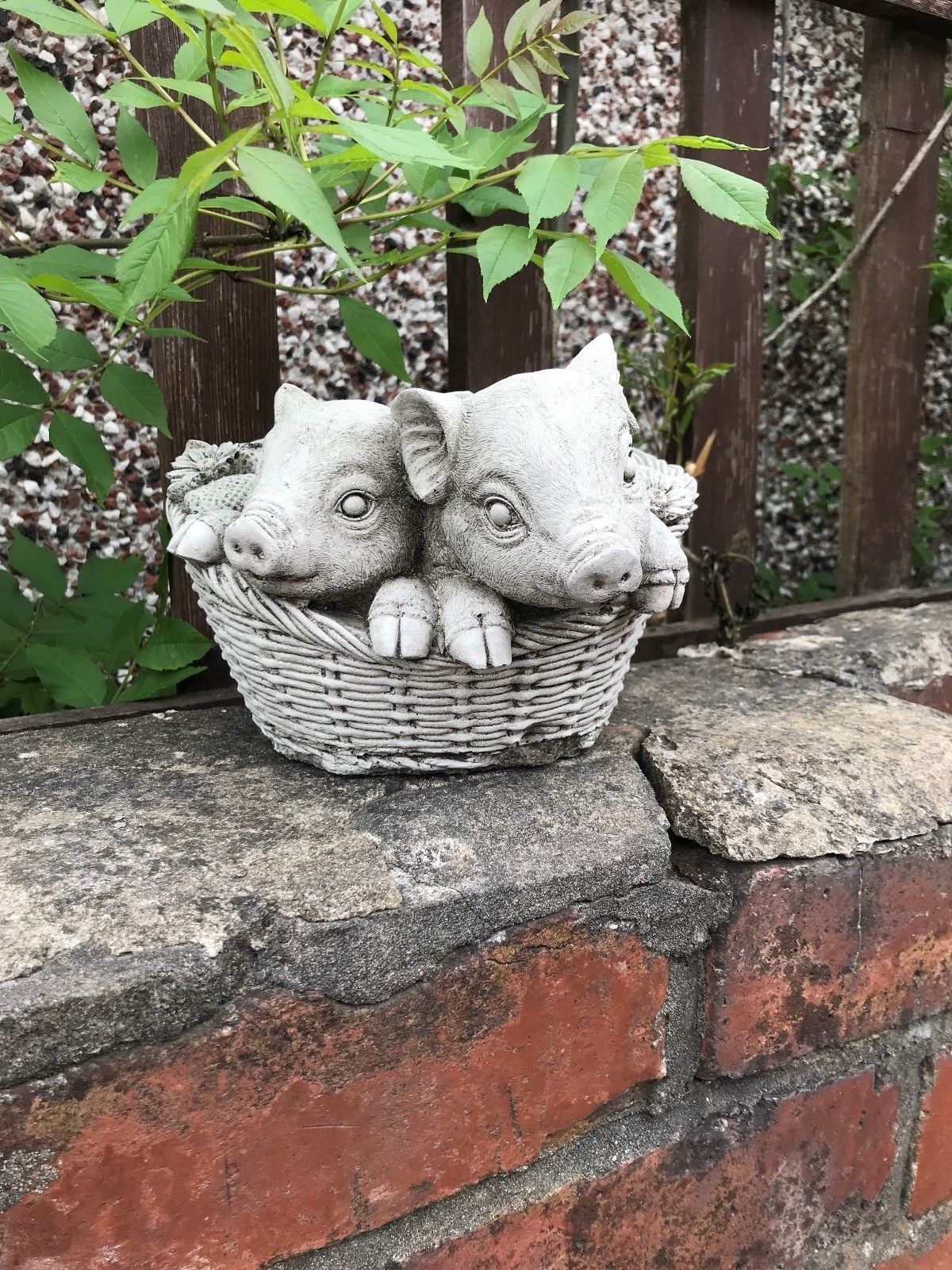 Charming stone pig planter ornament with piglet heads peeking from a basket. Crack-resistant garden decor ideal for patios and flower displays.