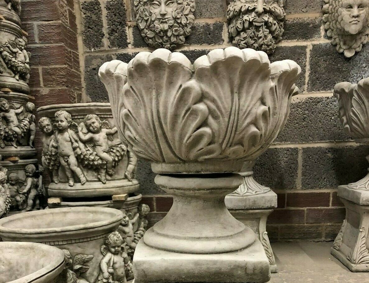 Antique-style small stone tulip planter displayed among decorative garden sculptures, perfect for patios or garden entrances.