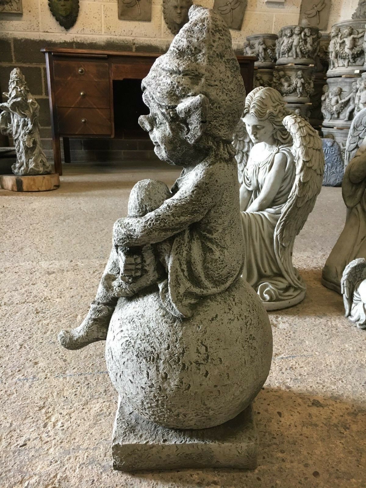 Stone Pixie on Ball Statue - Weatherproof Decor | Durable profile of a whimsical pixie statue seated on a stone ball, perfect for patios or lawns.