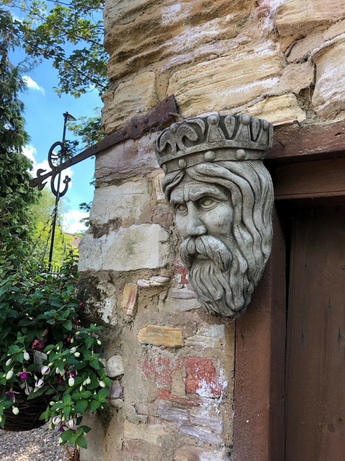Side view of Stone Crown King Garden Planter on outdoor wall, showcasing ornate crown design and weathered stone texture.