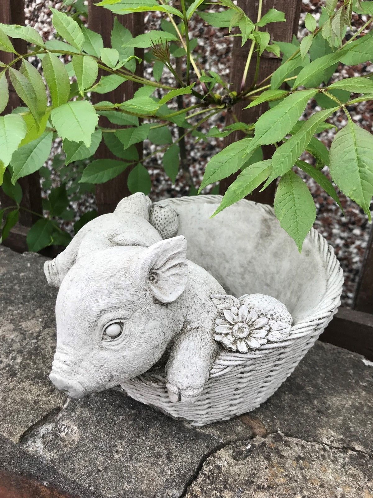 Detailed stone pig planter with floral and strawberry accents in a basket shape. Perfect for holding small plants in garden or patio settings.