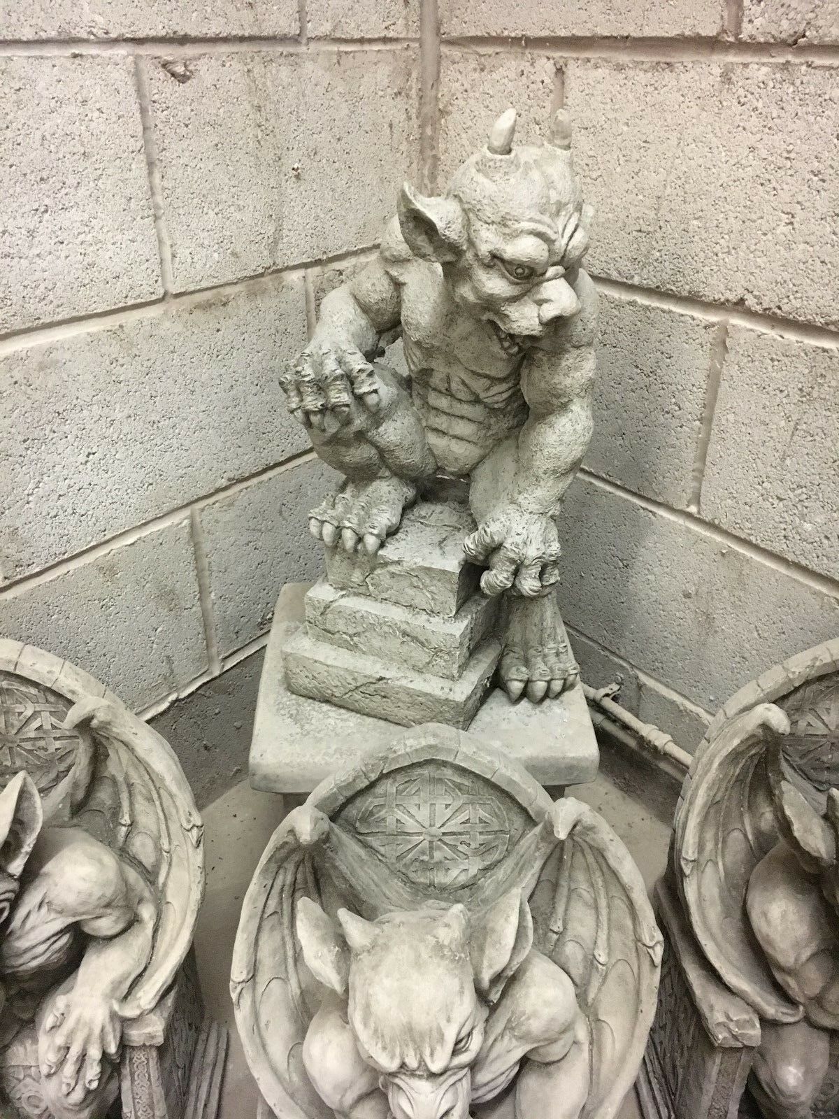 Side view of muscular stone gargoyle statue crouching on a pedestal, designed as a durable and menacing garden guardian.