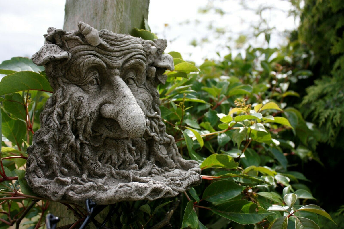 Handmade Greenman Bird Feeder Ornament with long nose displayed on a wooden post among lush garden foliage, perfect for outdoor charm.