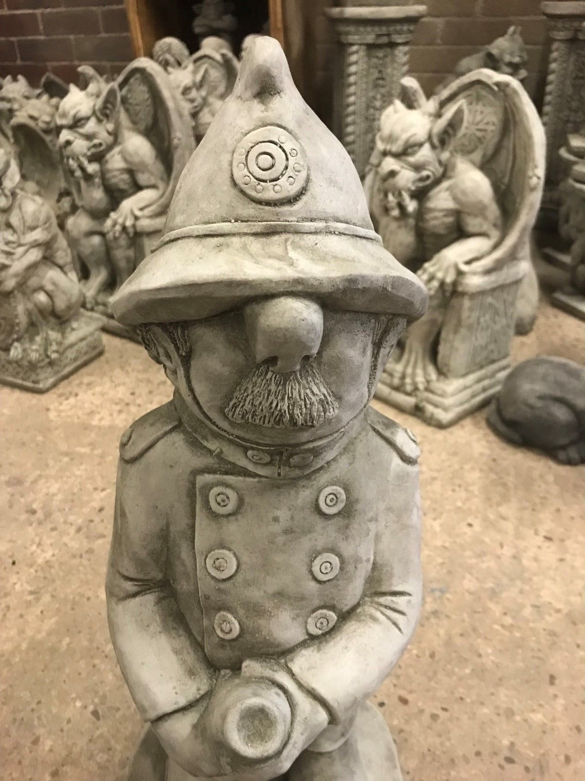 Close-up of limestone fireman statue with helmet and mustache, showcasing fine detailing for garden or porch decoration.